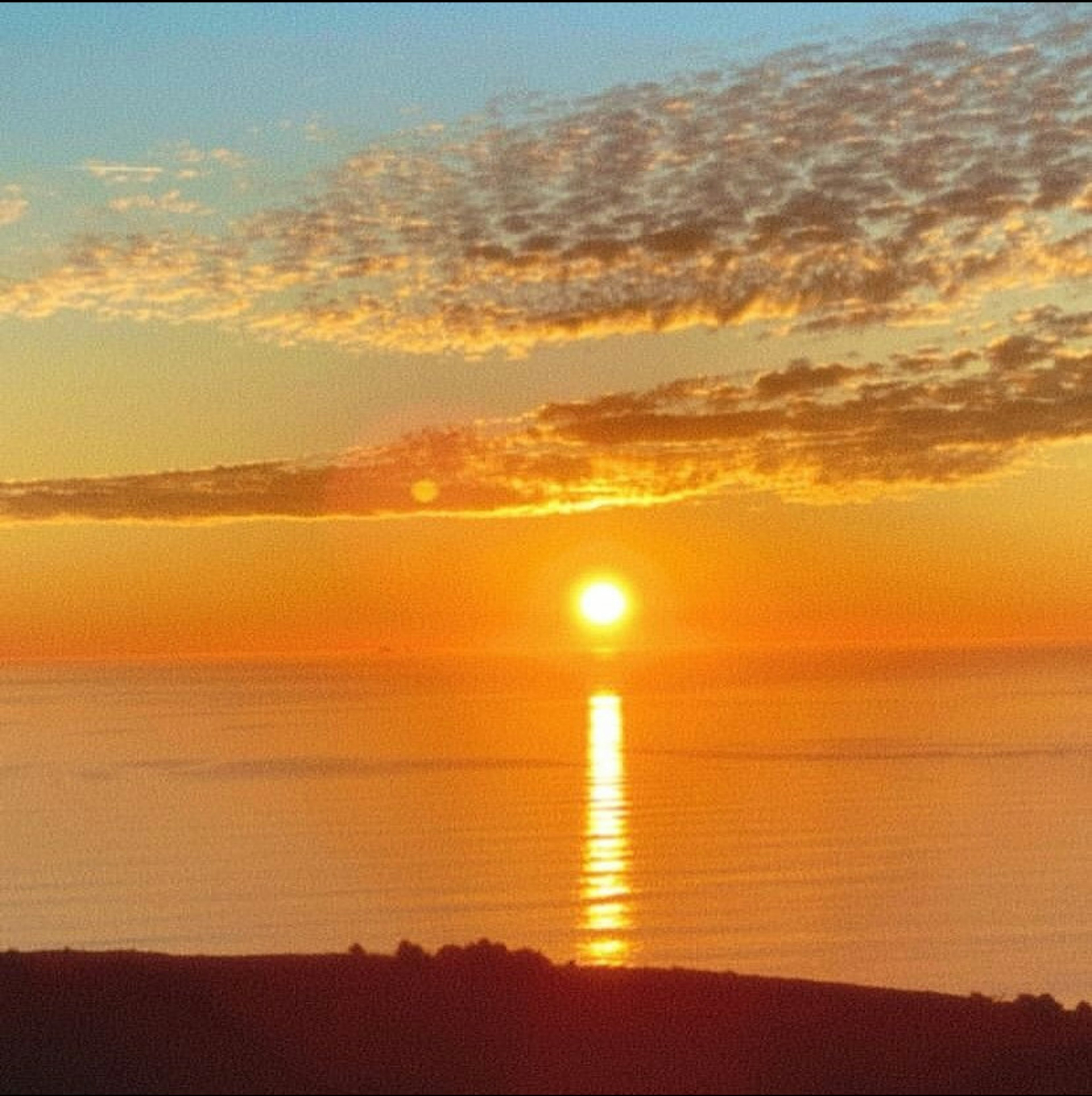 美しいオレンジ色の夕日が海に沈む様子と雲のパターン