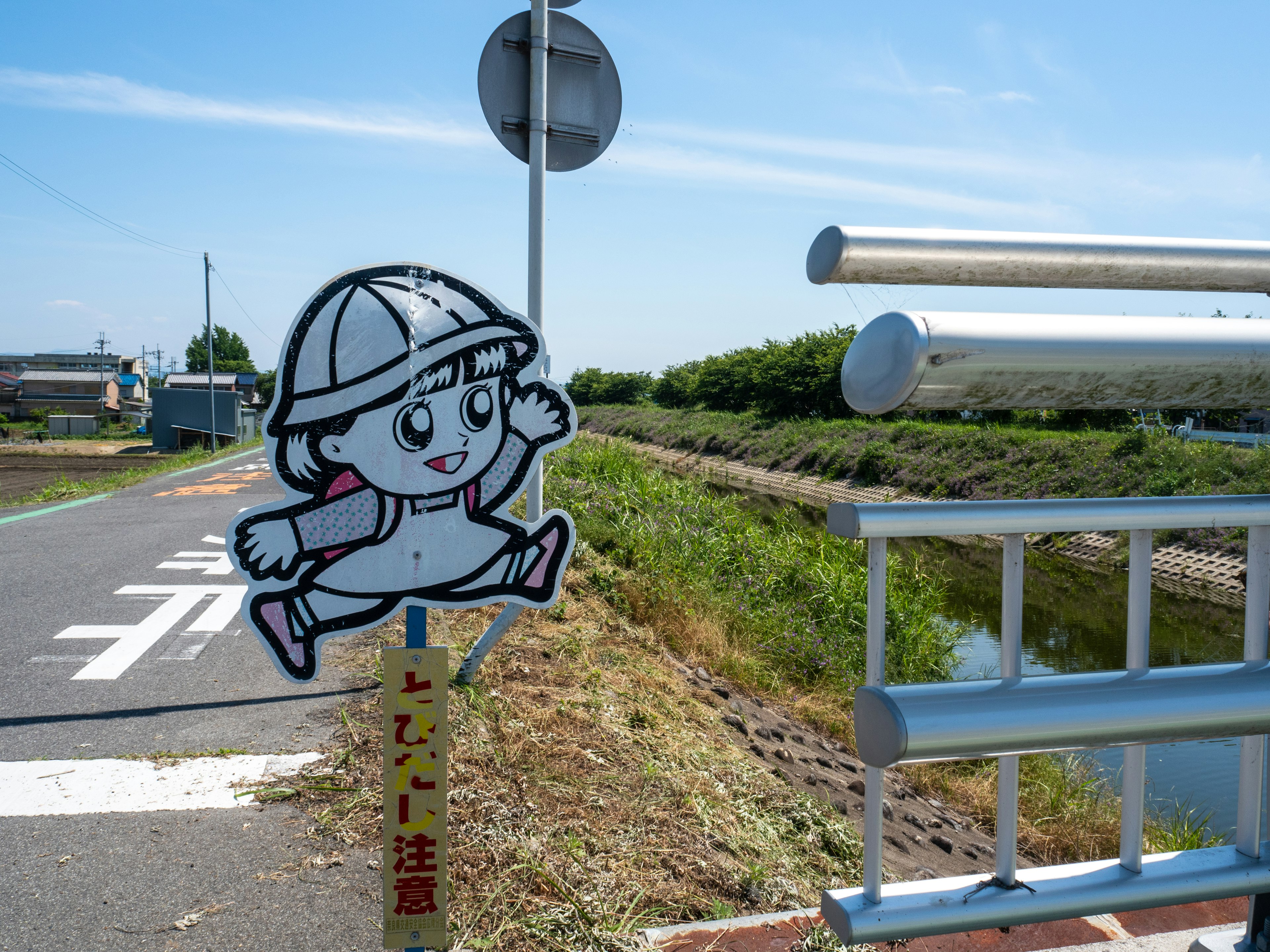 A sign featuring a child character near a riverbank Bright blue sky and green landscape