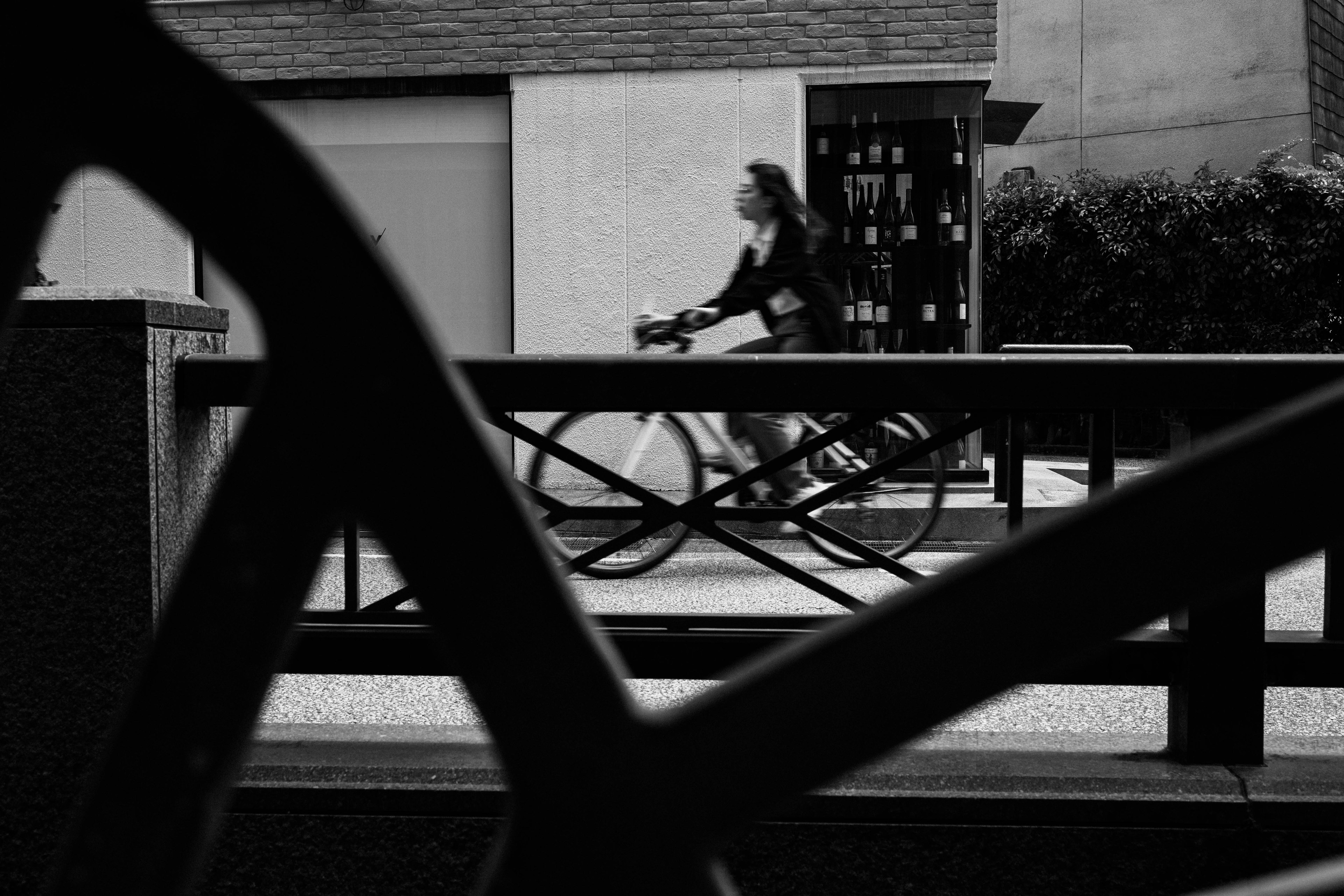 Una mujer montando una bicicleta pasando en un entorno en blanco y negro