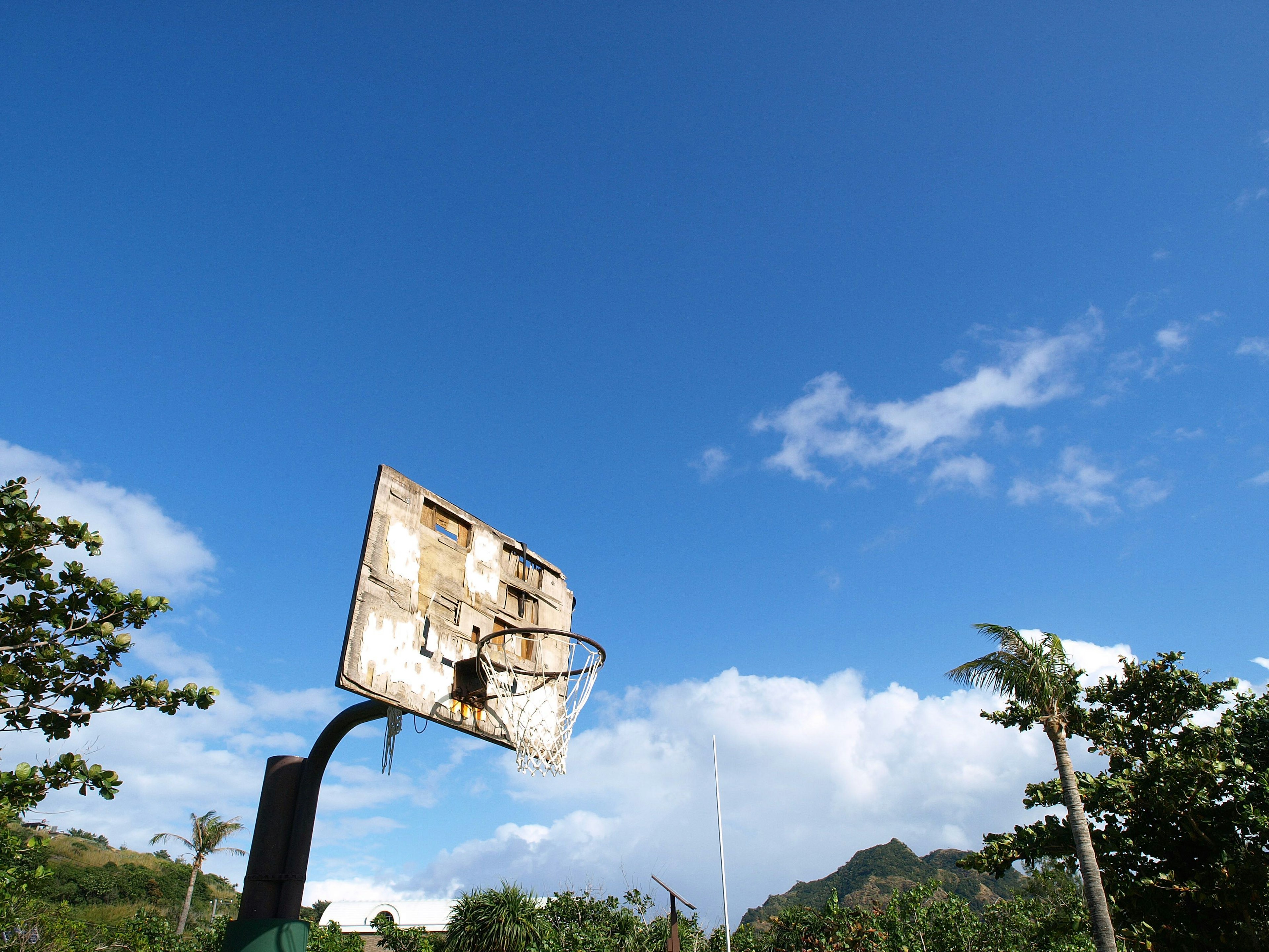 Vecchio tabellone da basket e rete sotto un cielo azzurro