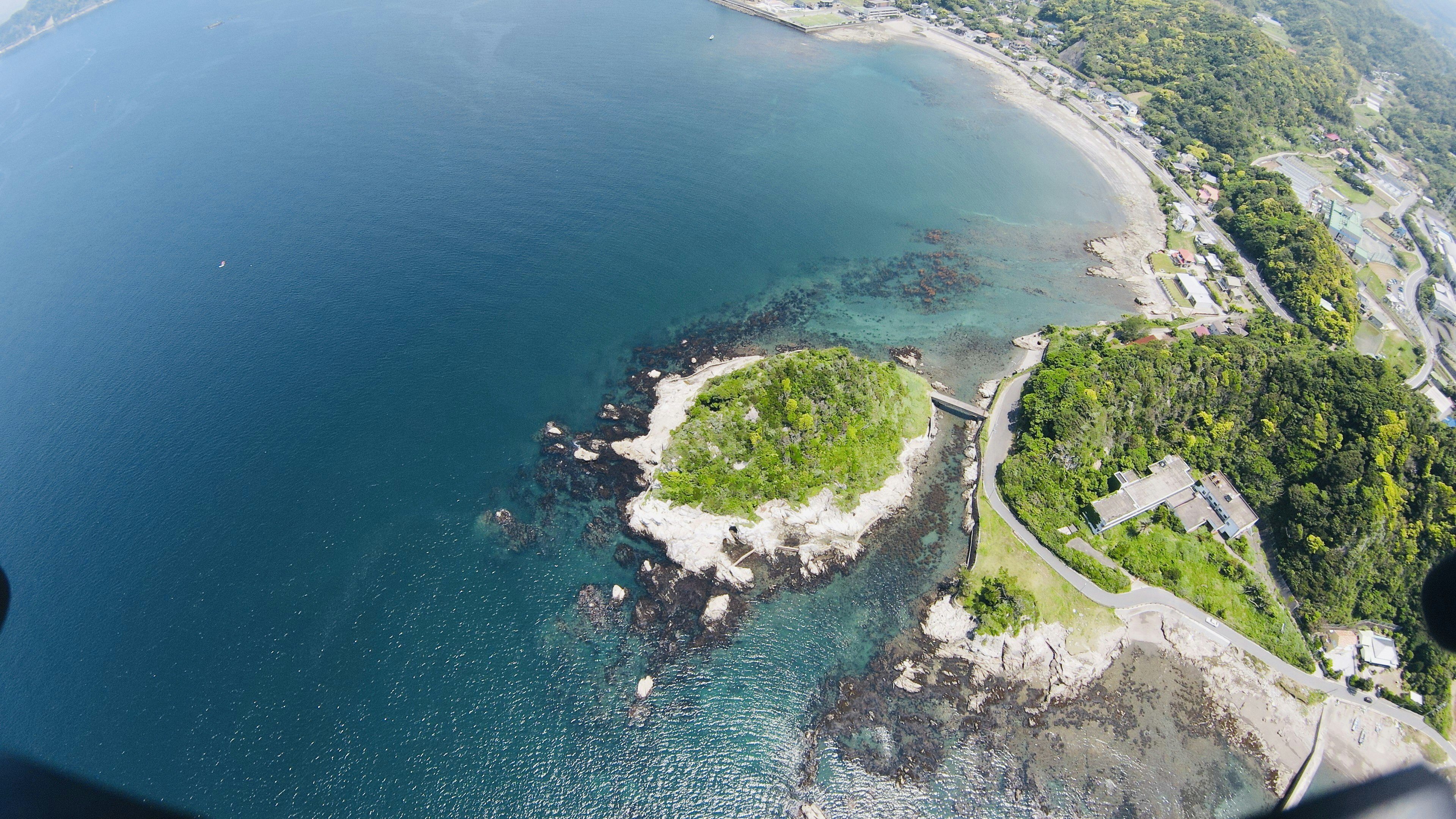 Aerial view of a small island surrounded by blue water and lush green coastline