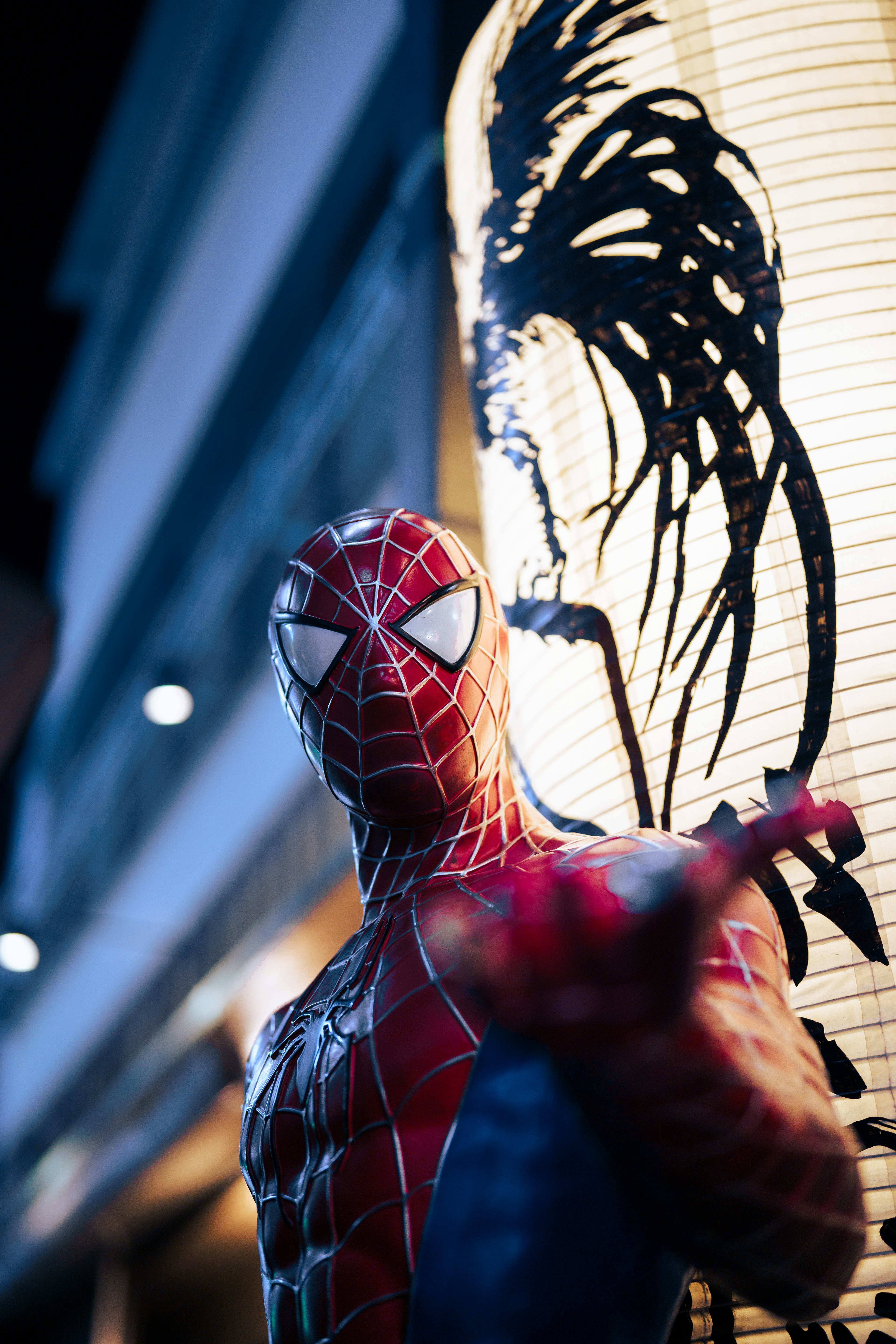 スパイダーマンが夜の街並みでポーズをとっている背景に和風の提灯