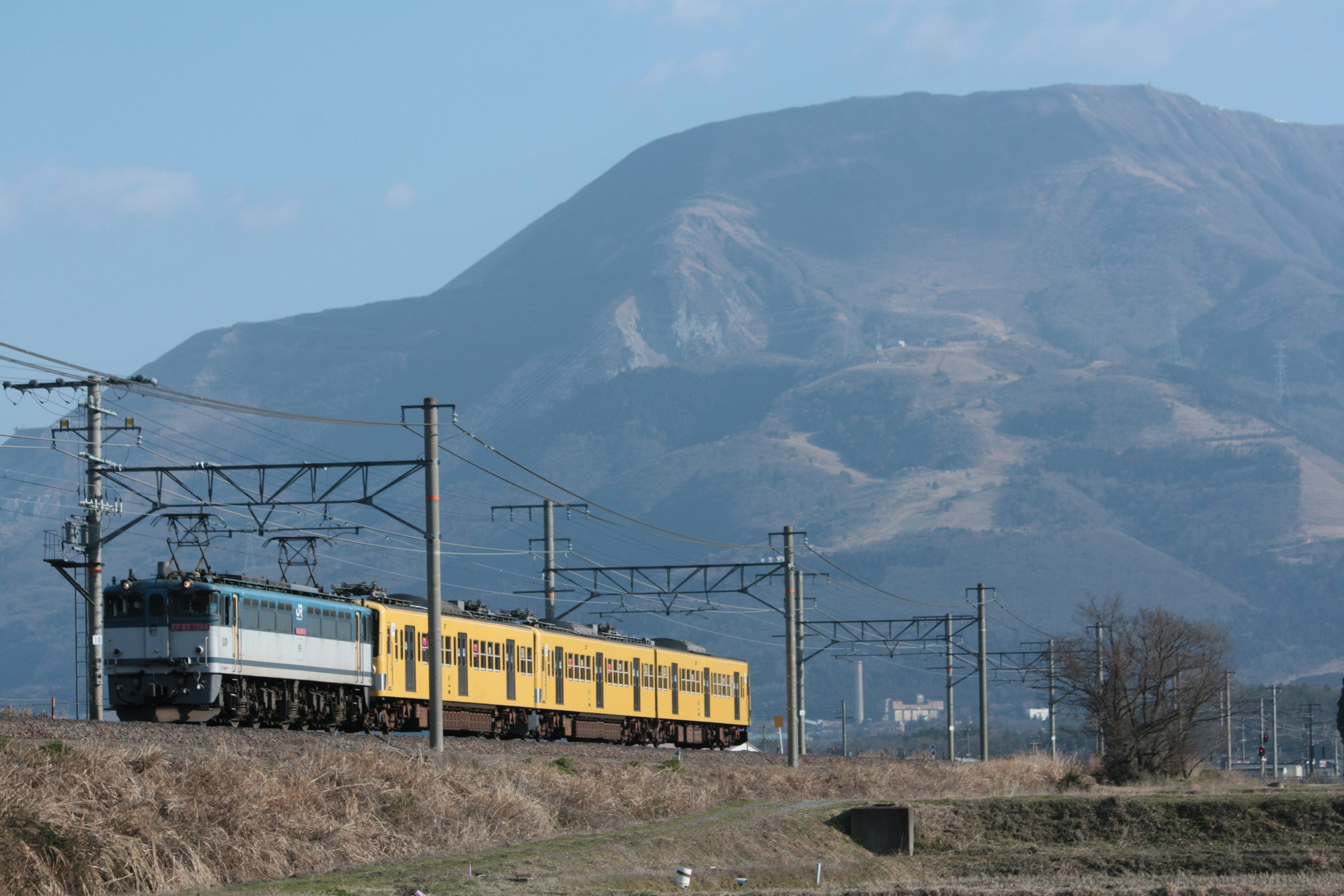 Un tren amarillo viajando con un fondo montañoso