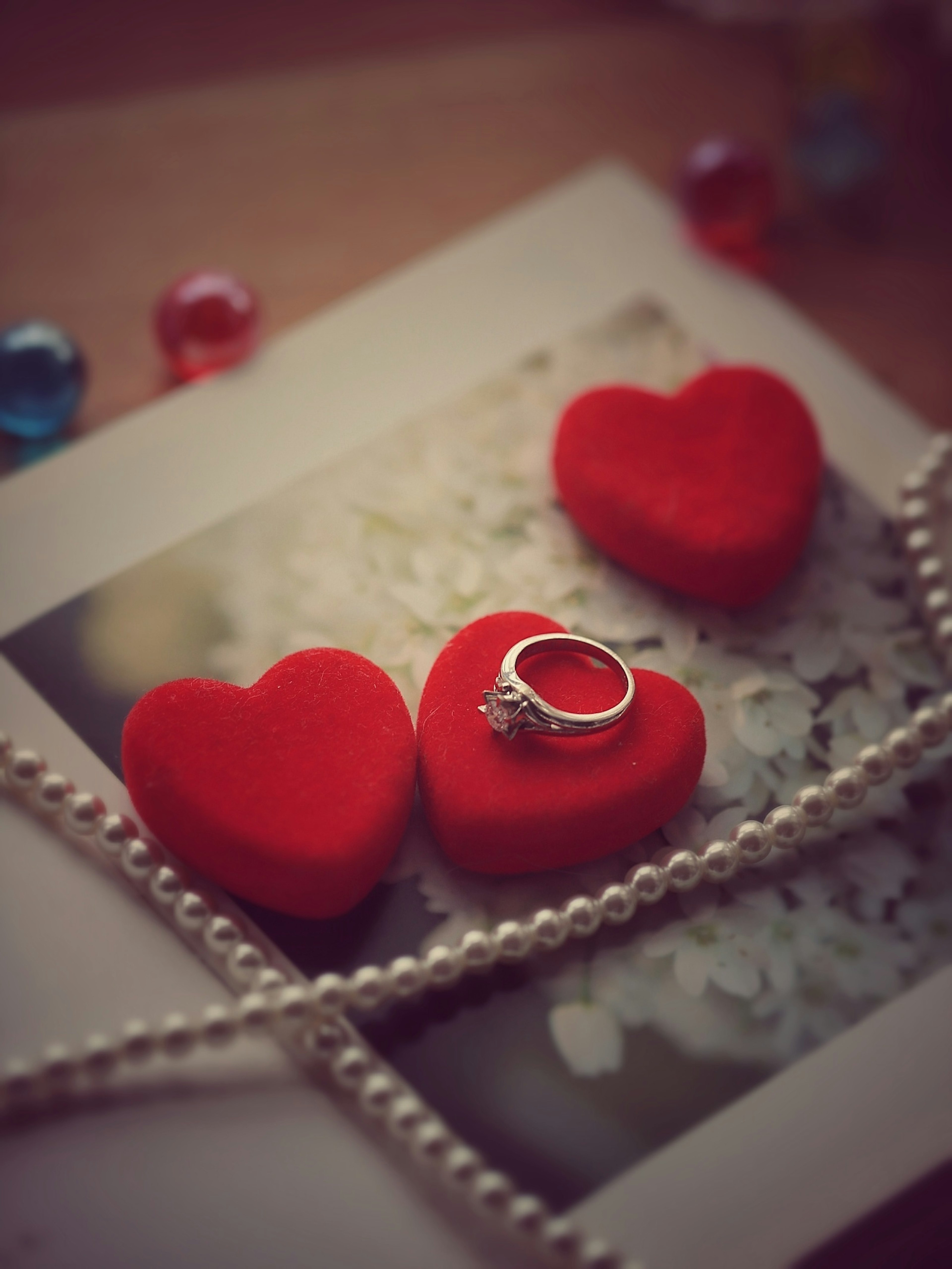 Decoraciones en forma de corazón rojo y un anillo sobre una foto