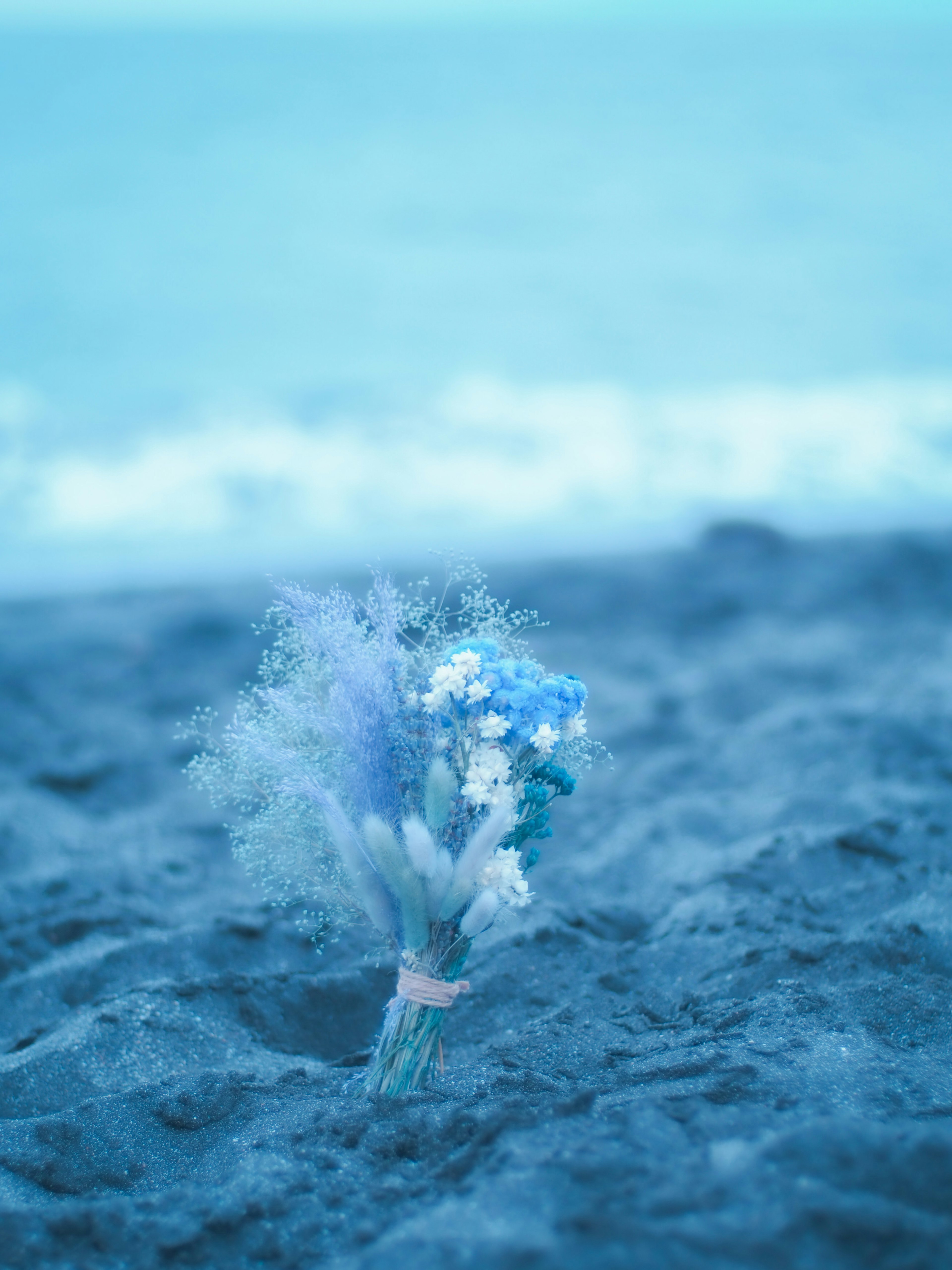 青い花束が砂浜に置かれている海の風景