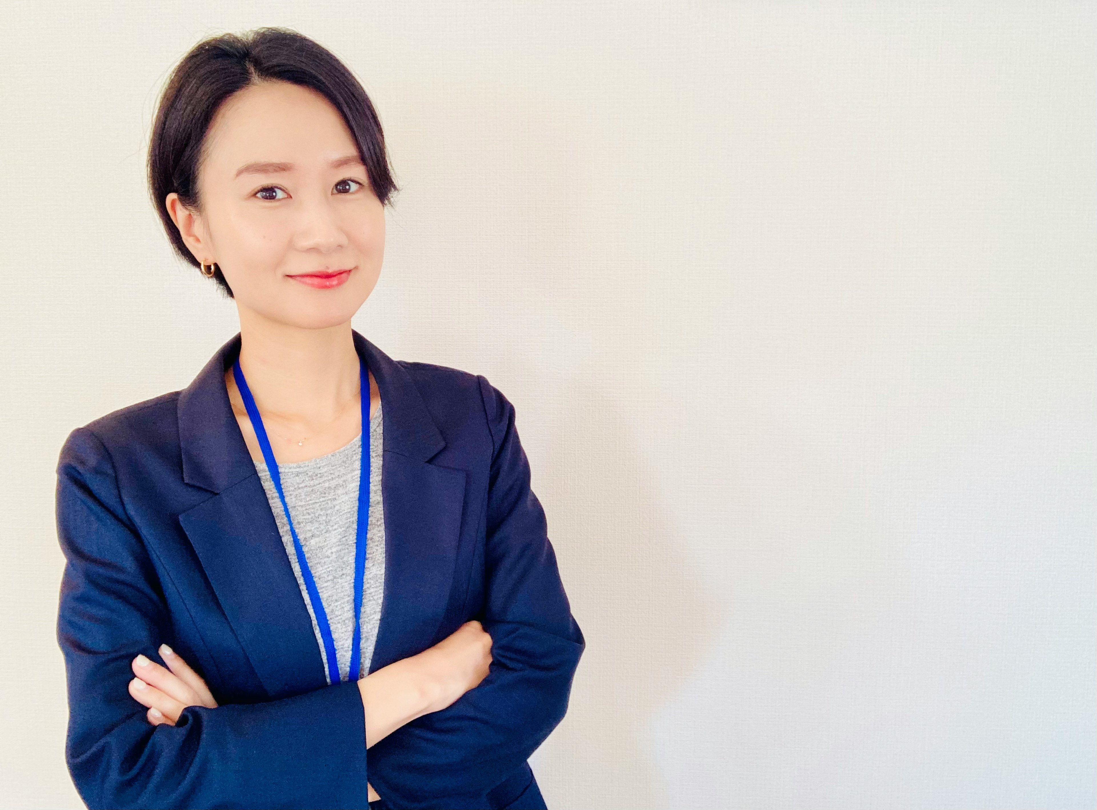 A woman in a business suit smiling with her arms crossed