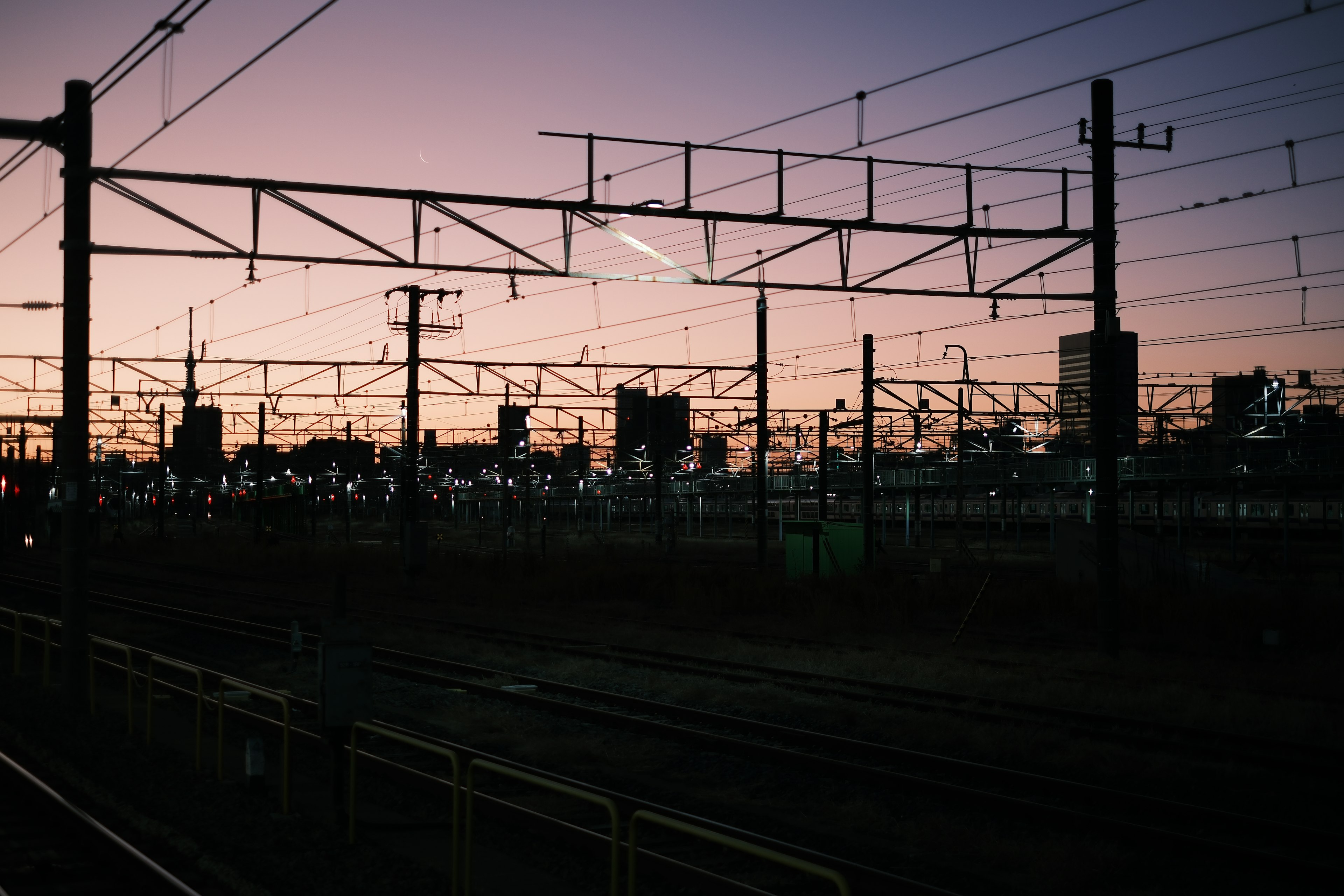 夕暮れ時の鉄道の架線とシルエットのビル群