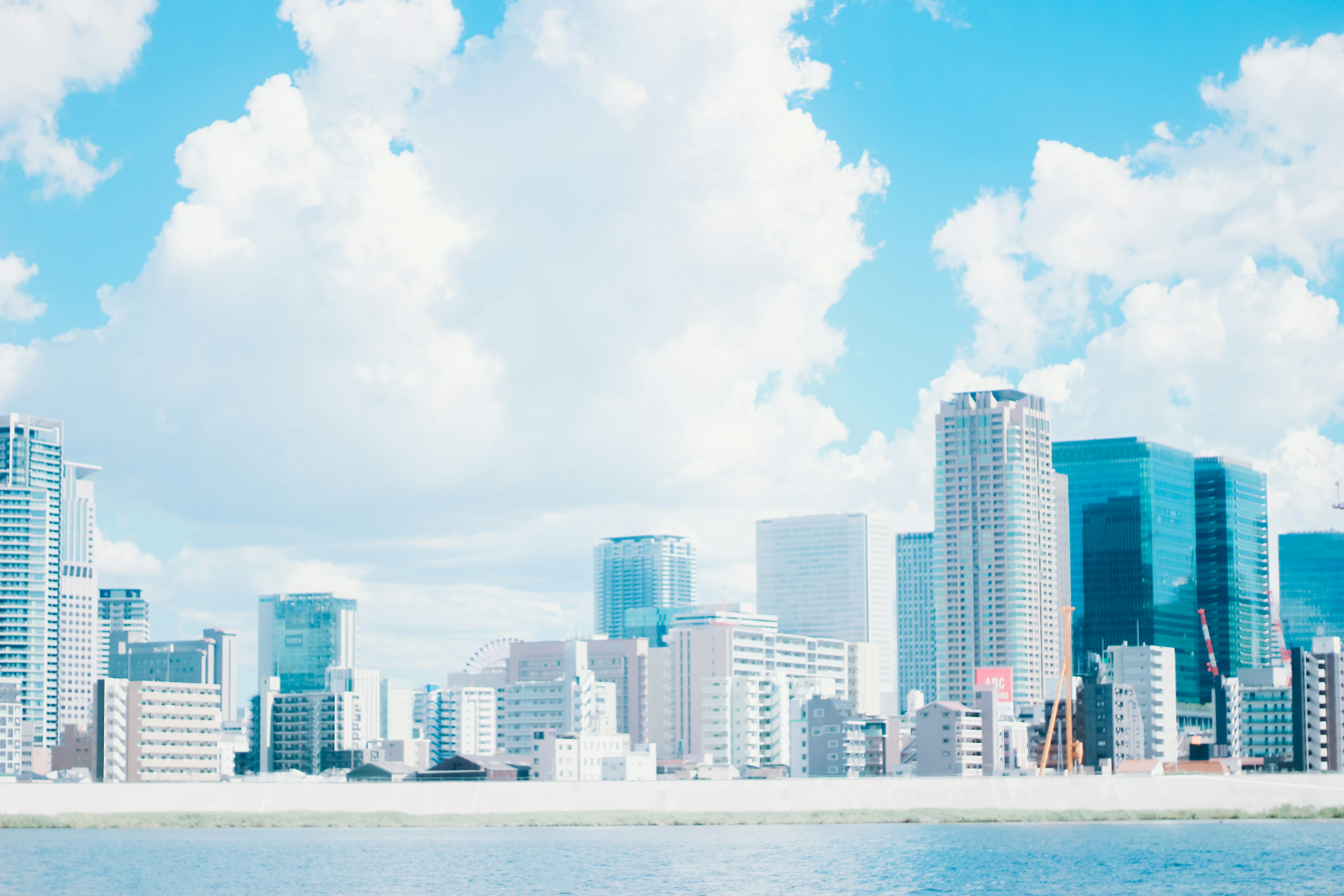 City skyline featuring tall buildings under a blue sky with fluffy white clouds