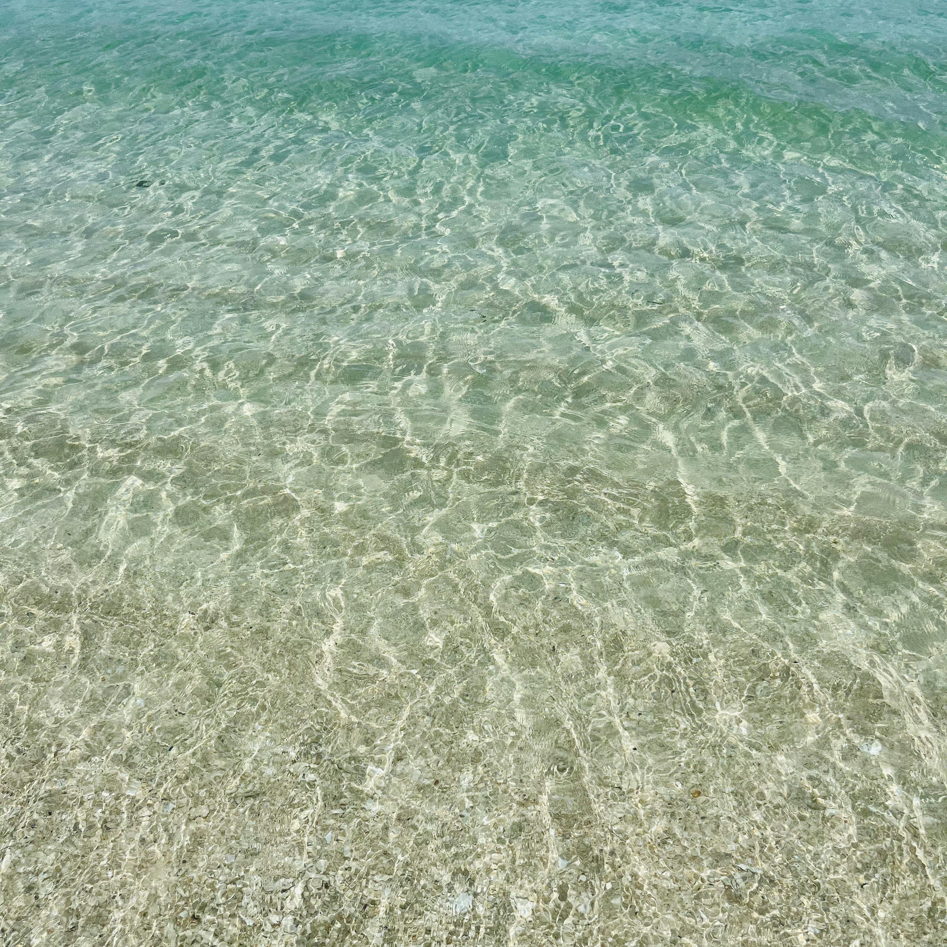 Acqua limpida su una spiaggia di sabbia con leggere increspature