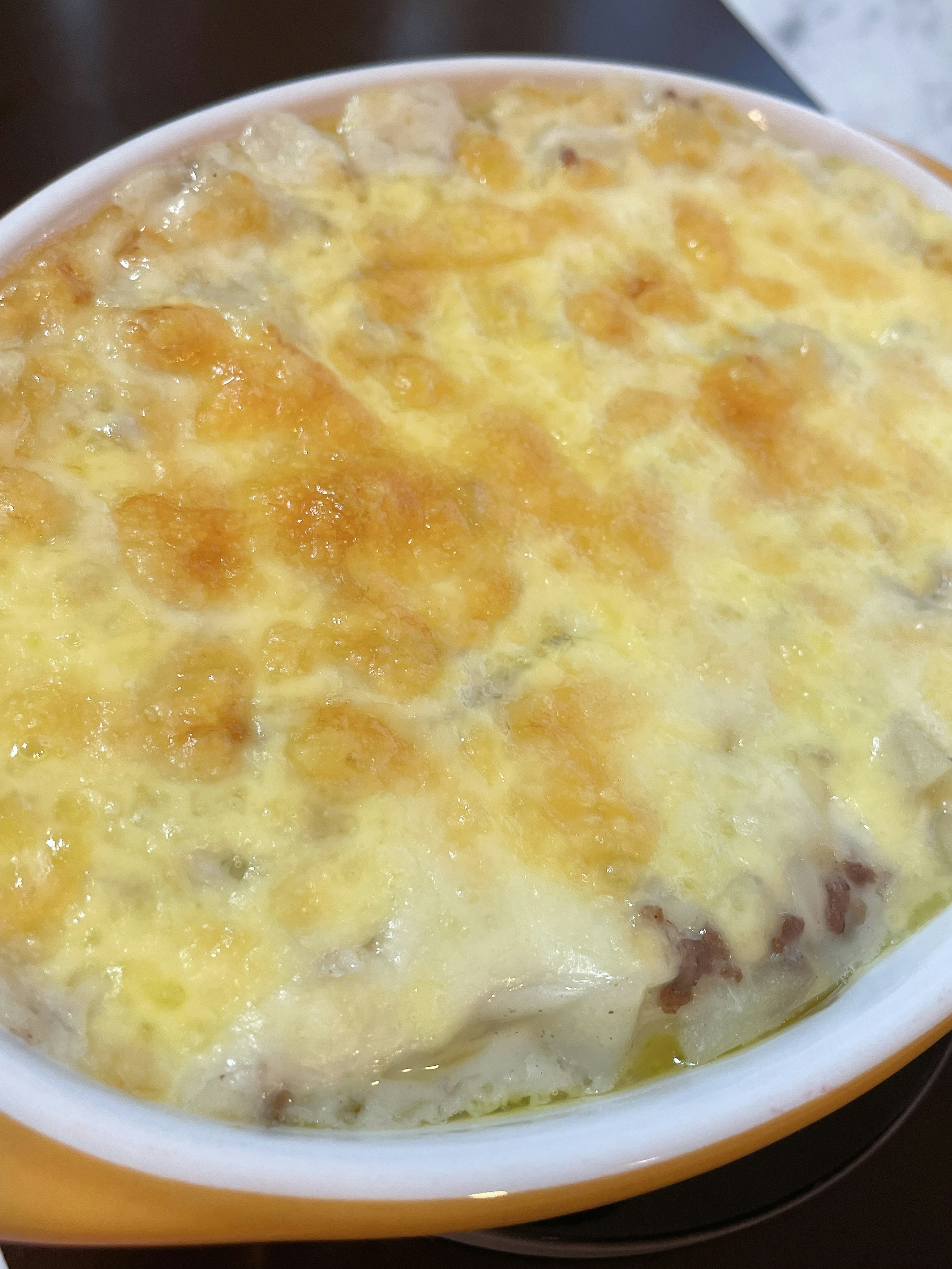 Close-up hidangan gratin krim yang ditutupi keju leleh