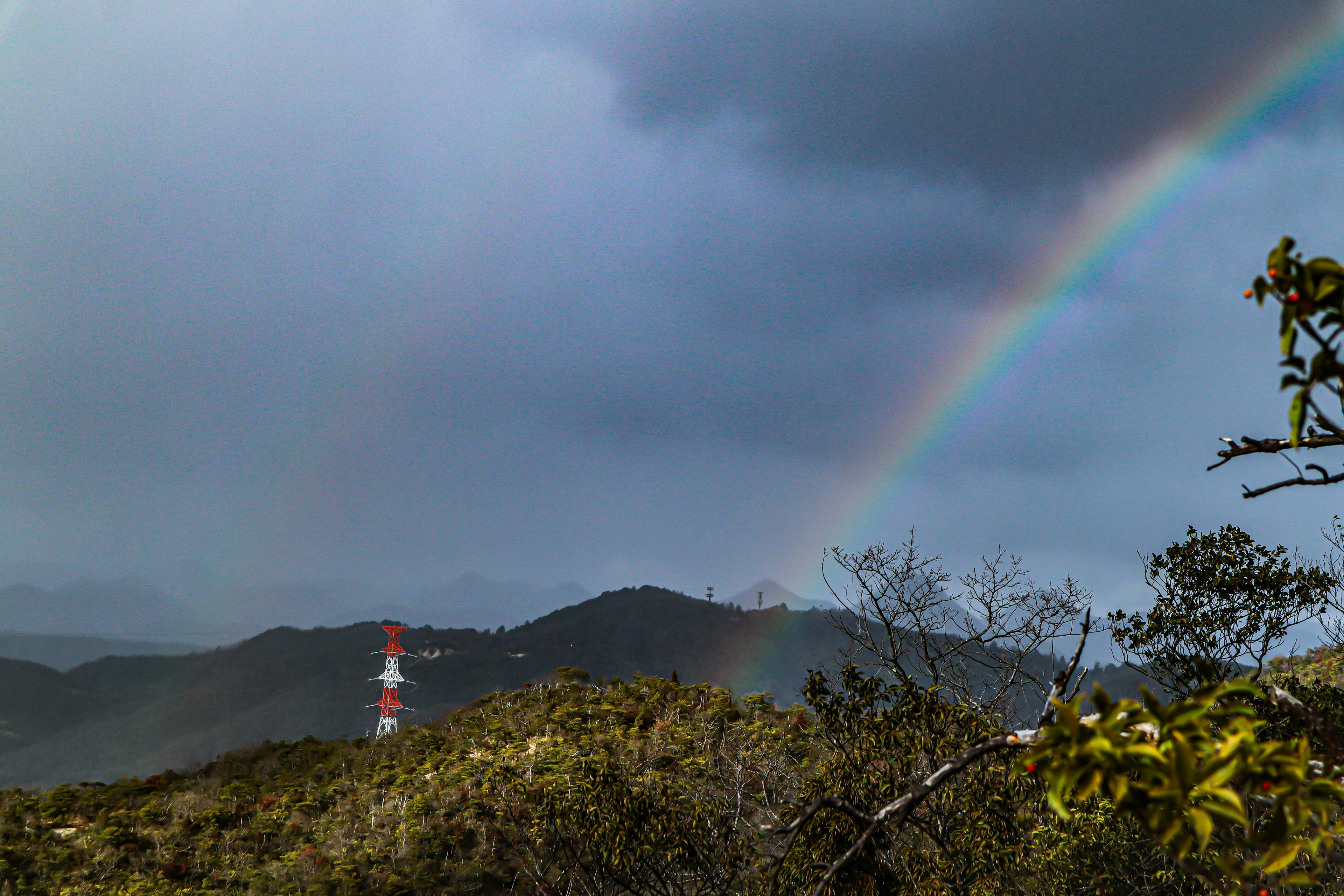 Scenic view of mountains with a rainbow and a communication tower