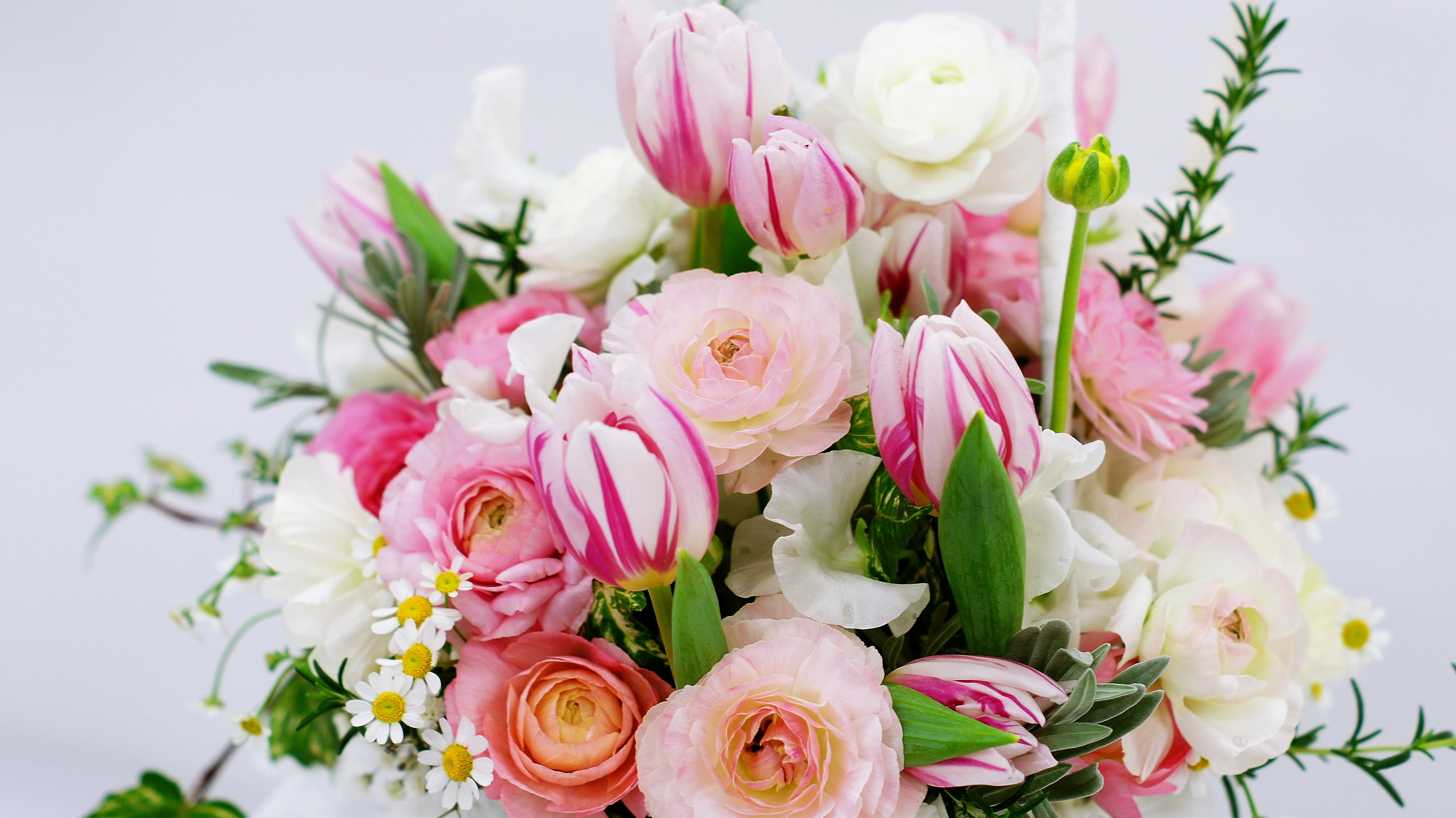 Un bouquet vivace con tulipani rosa e rose bianche tra altri fiori