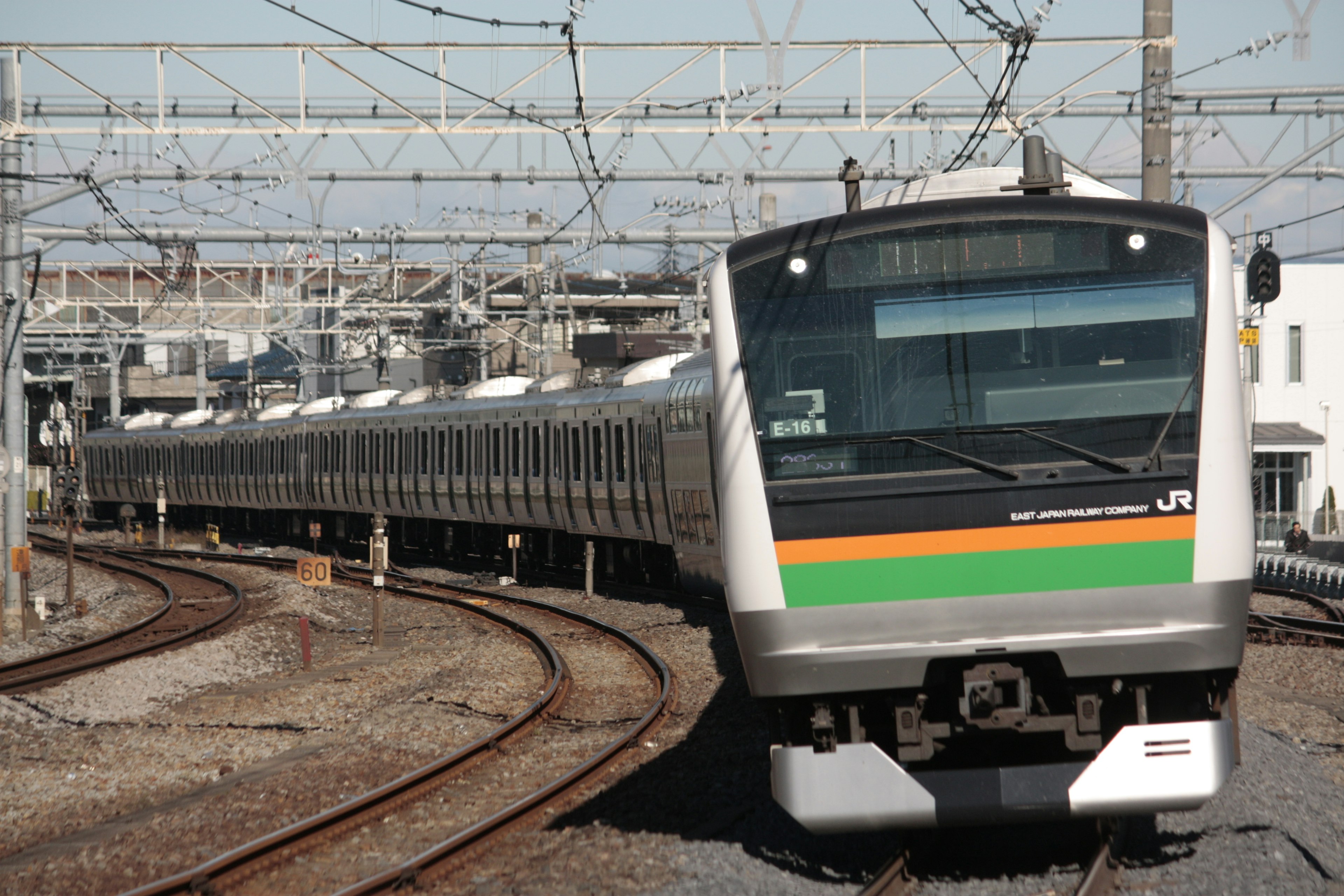 Un tren japonés con rayas naranjas y verdes navegando por vías curvas