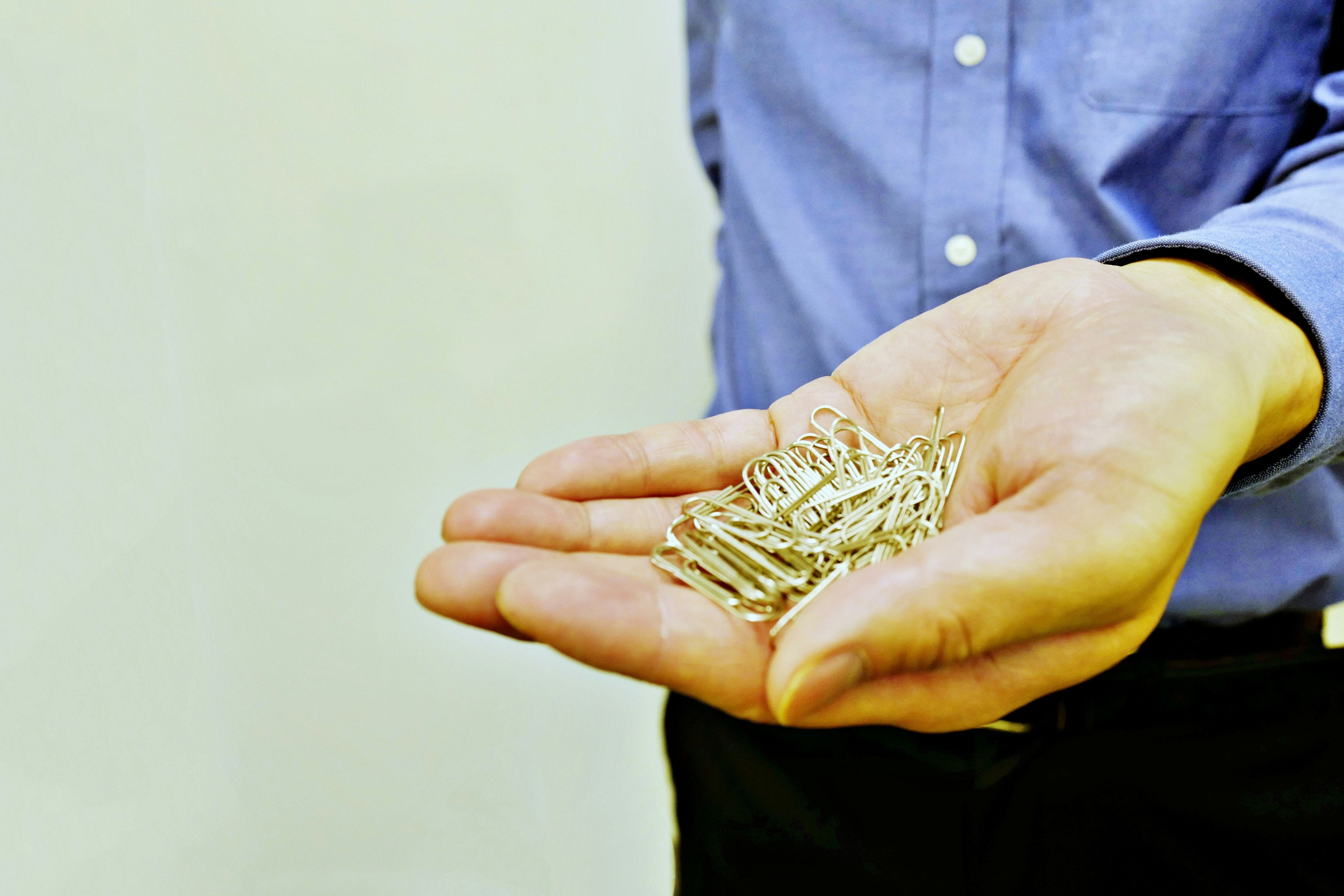 A man's hand holding silver nails