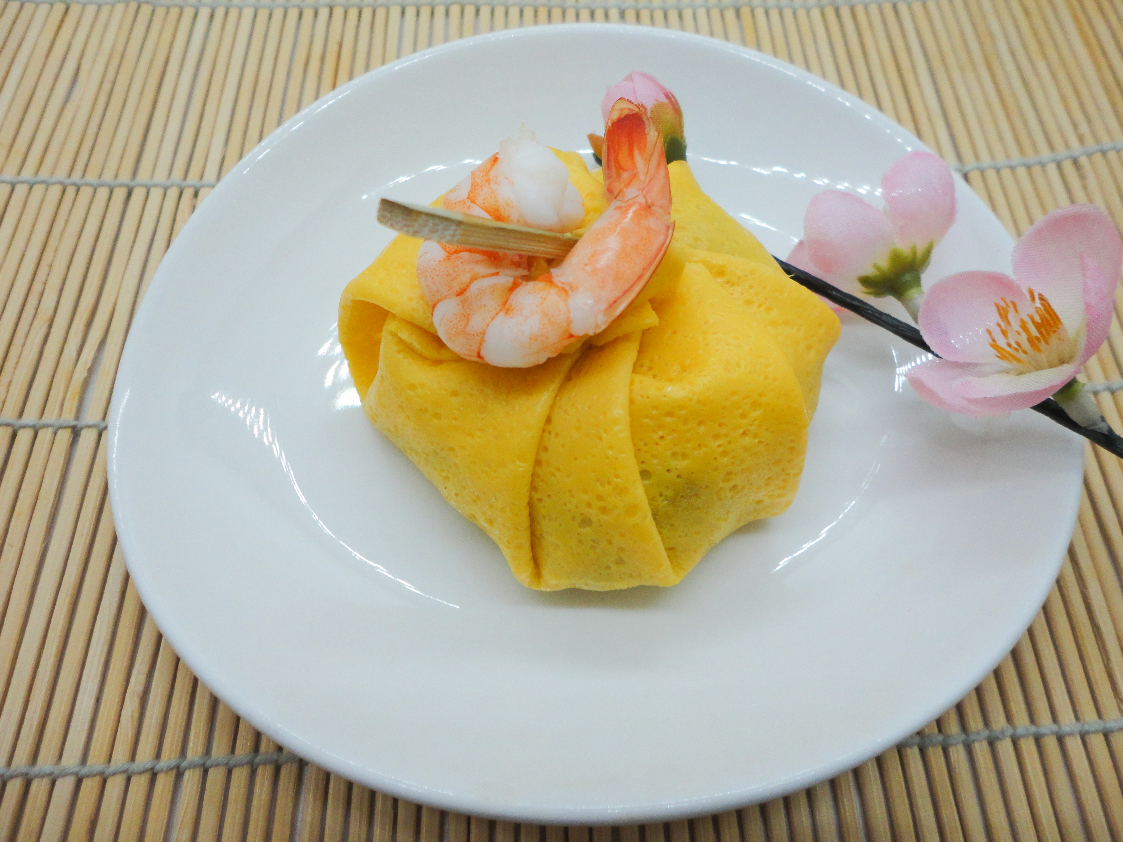 Yellow egg wrap dish topped with shrimp