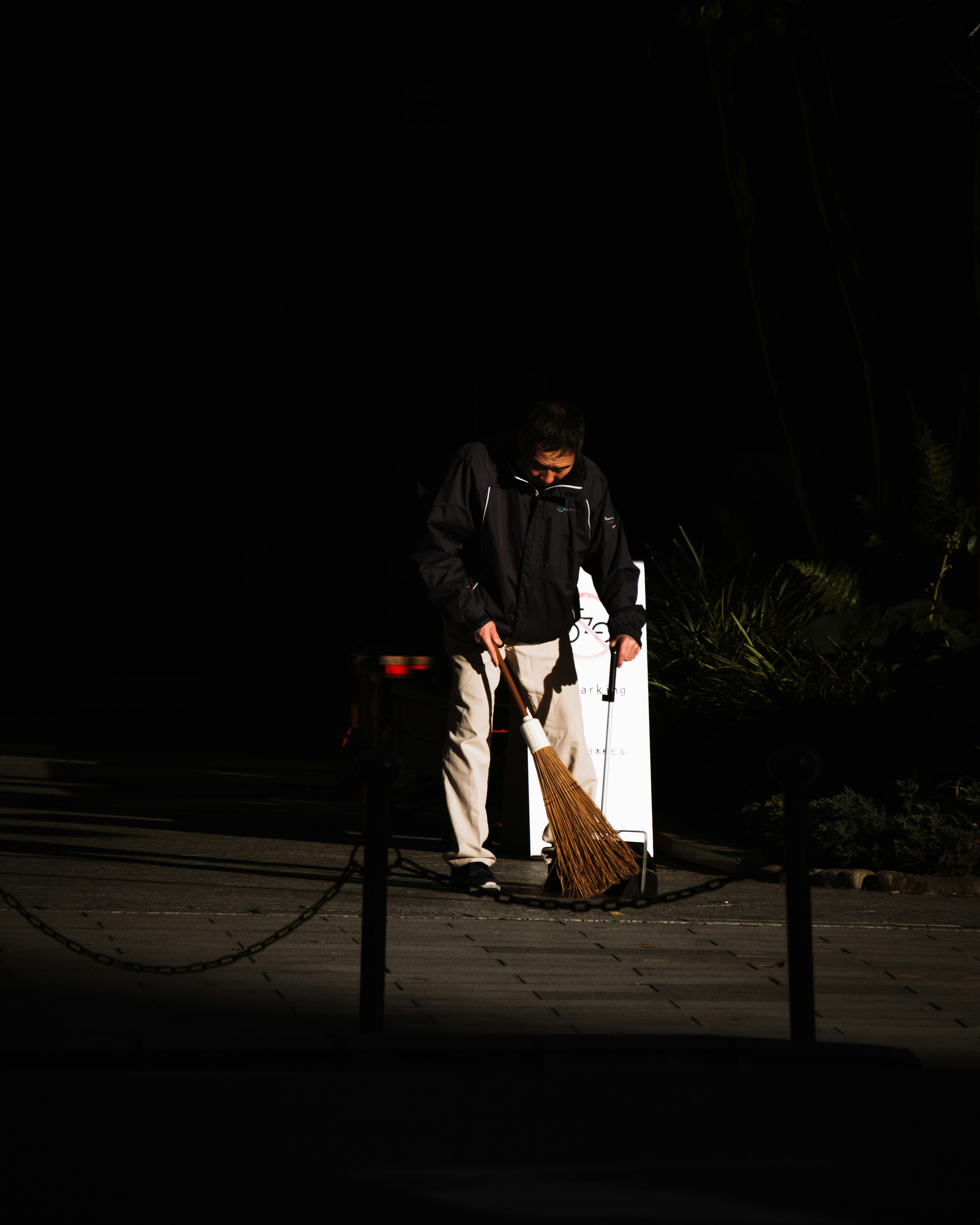 Person sweeping in a dark setting silhouette of a worker with cleaning tools