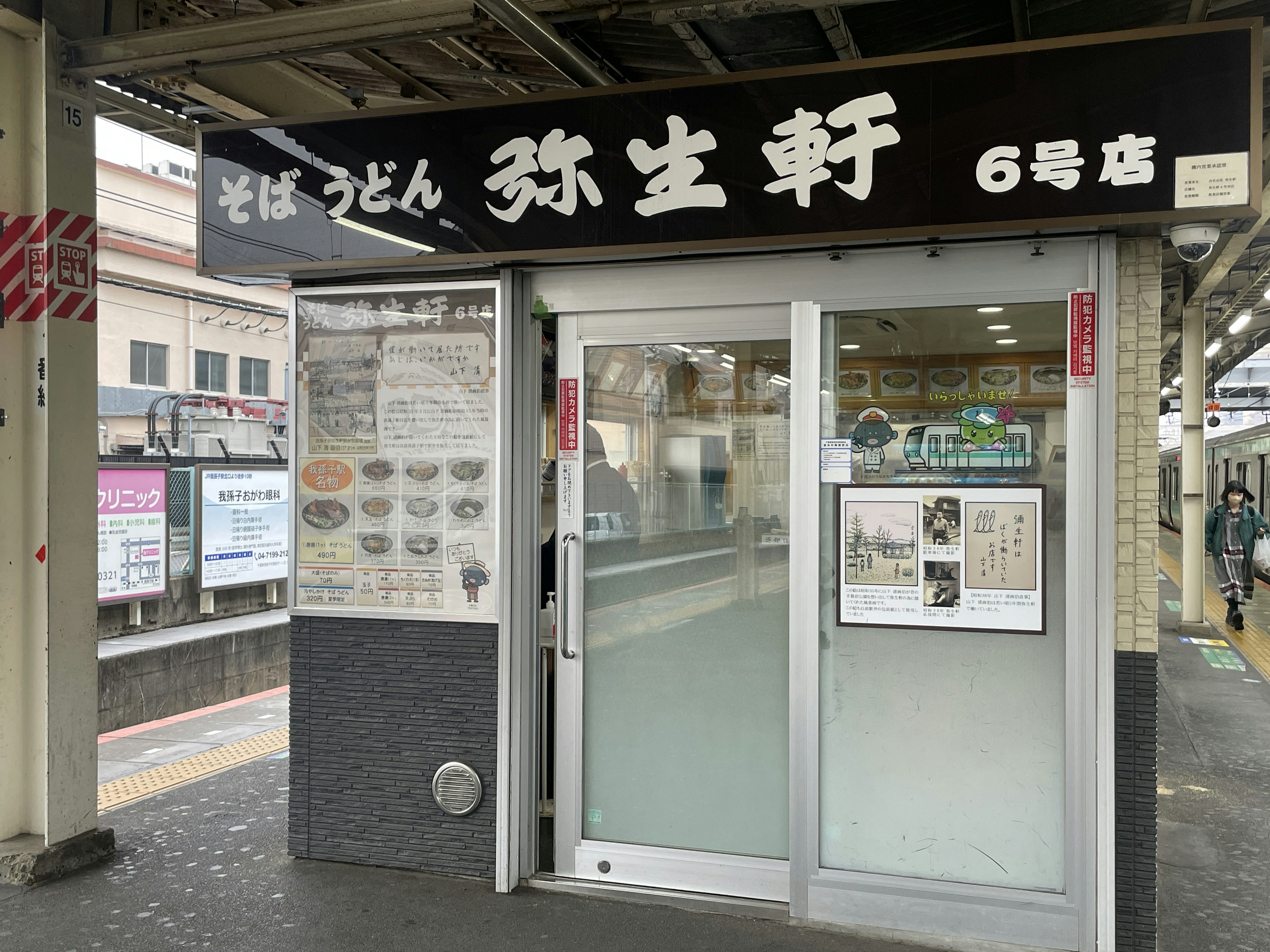 Pintu restoran udon yang terletak di stasiun kereta dengan pintu kaca dan menu yang ditampilkan