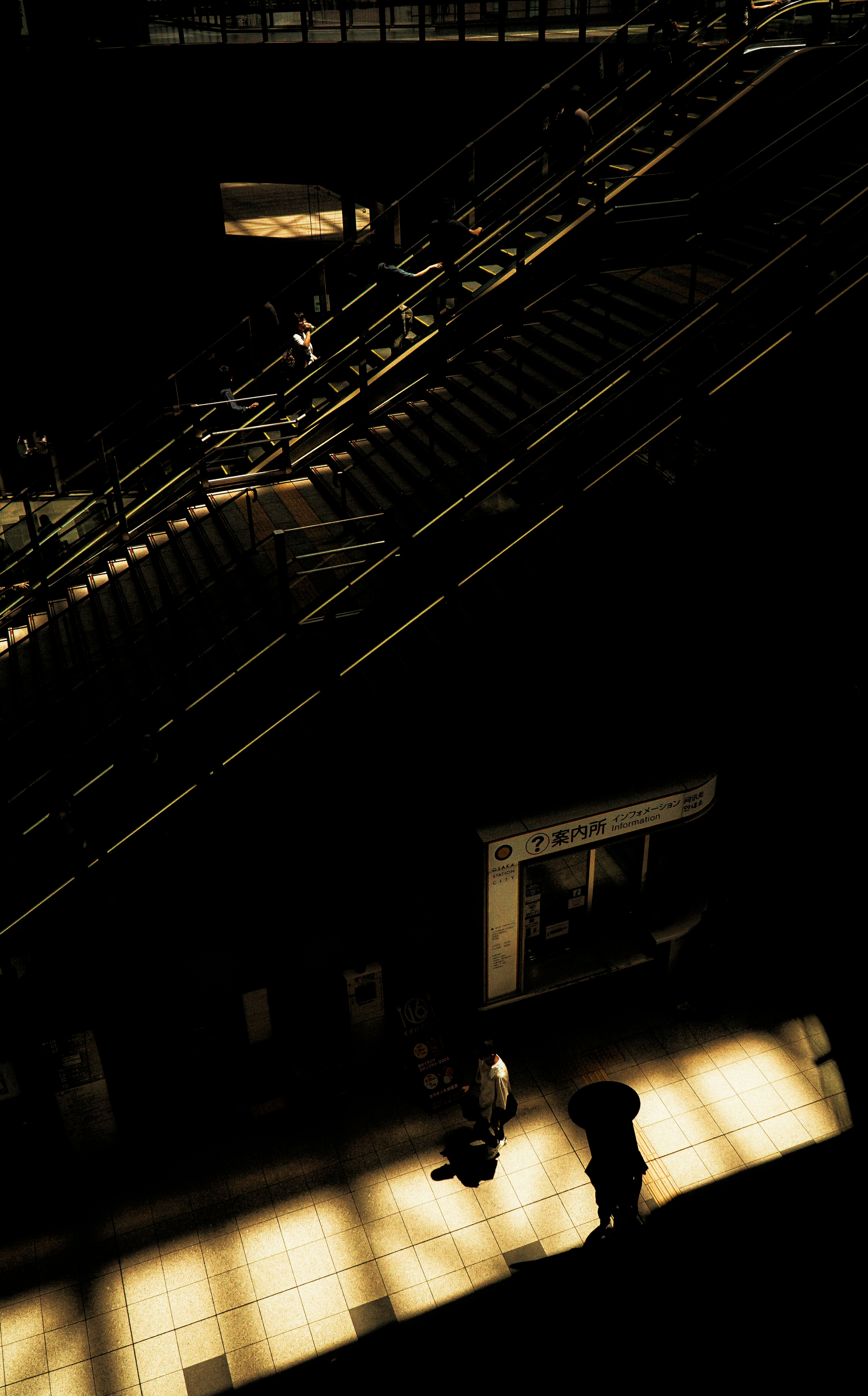 Contrast of people and light against a dark staircase