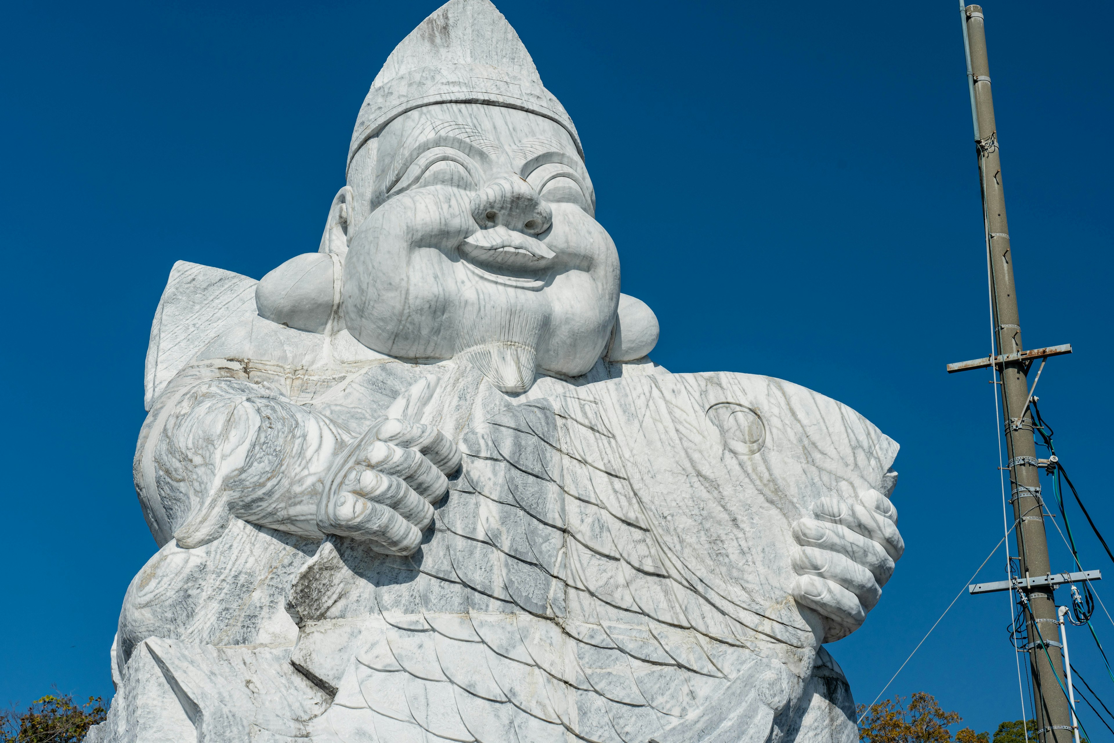 Grande statua bianca sorridente con le mani che tengono qualcosa