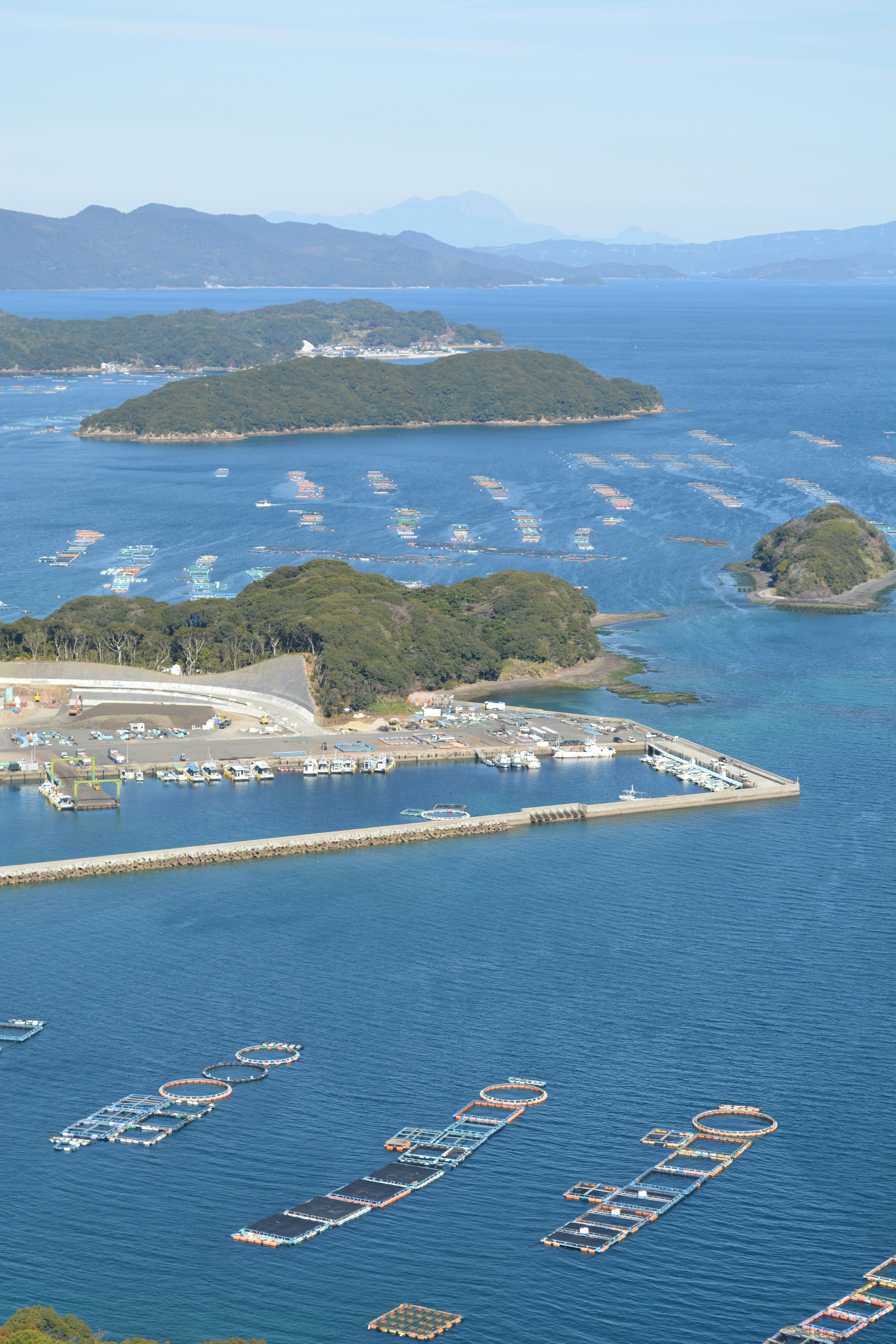 Aerial view of blue sea with floating fishing boats featuring a harbor and islands