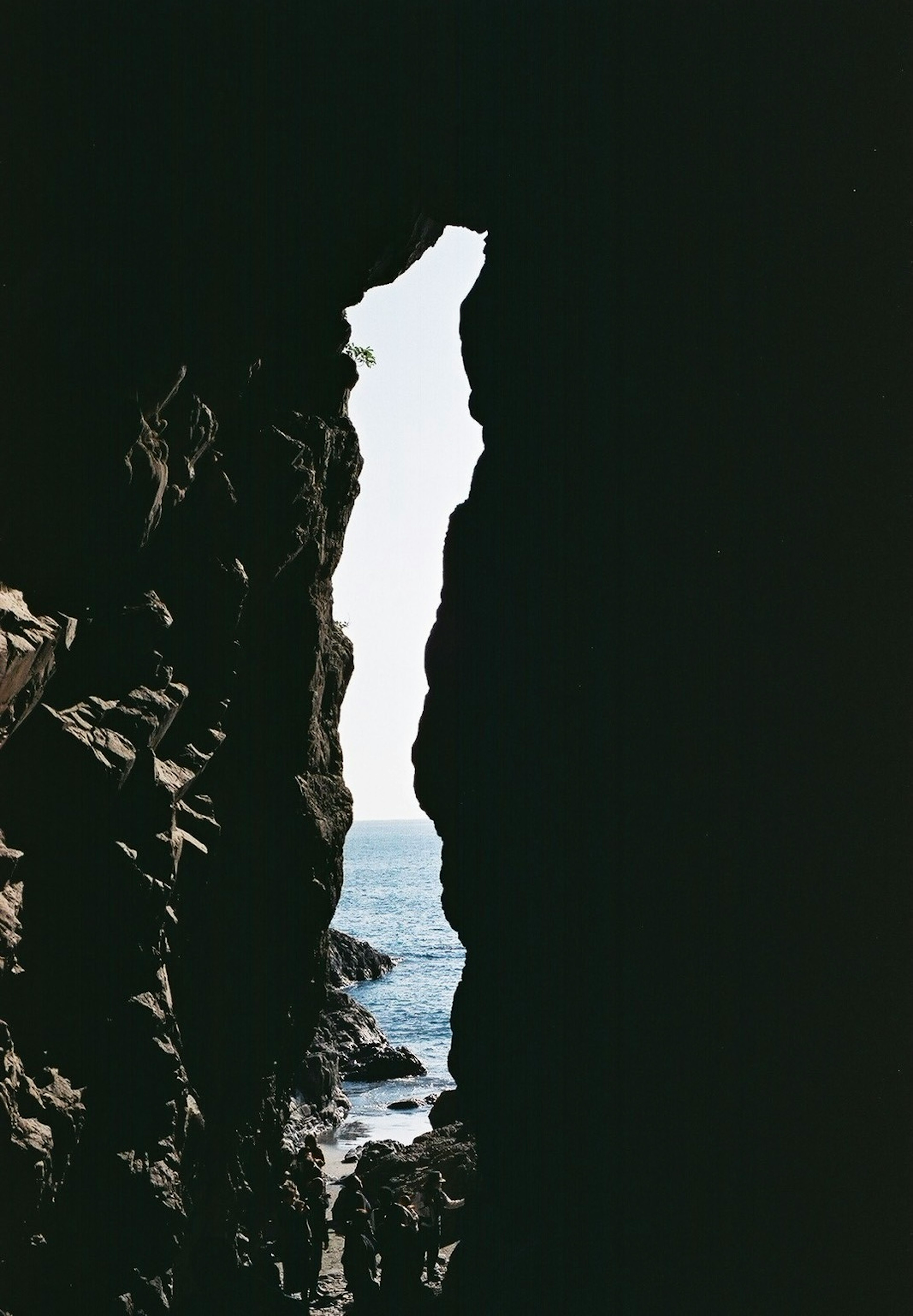 View of the sea through a narrow rock crevice dark rocky frame