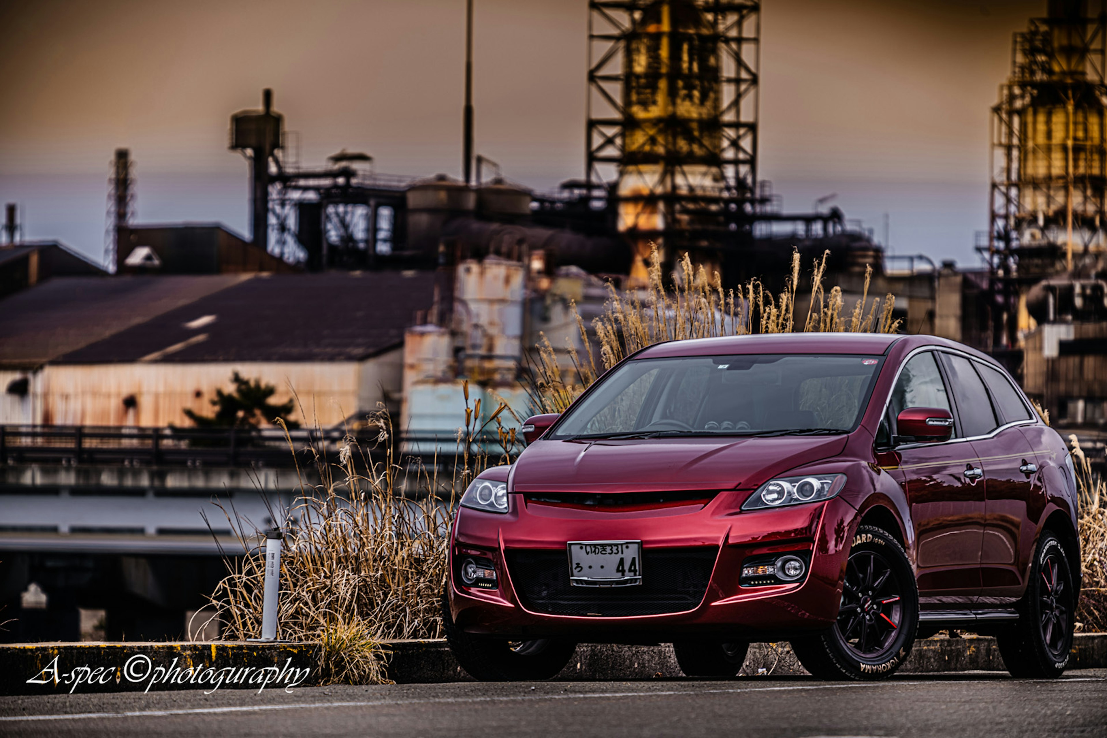 A red car parked in front of an industrial background