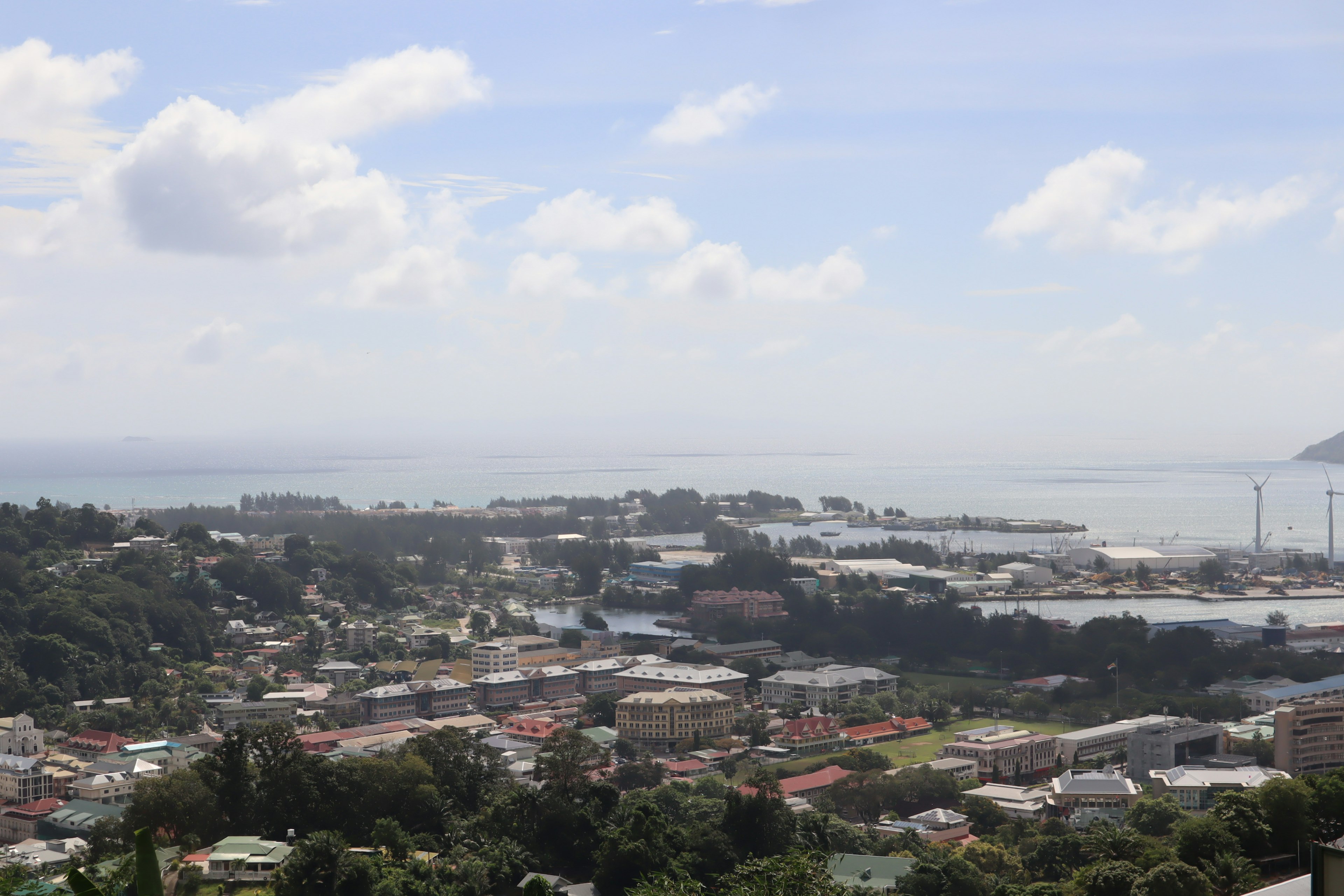 Vue panoramique d'une ville côtière avec ciel bleu et nuages blancs arbres verts et maisons colorées