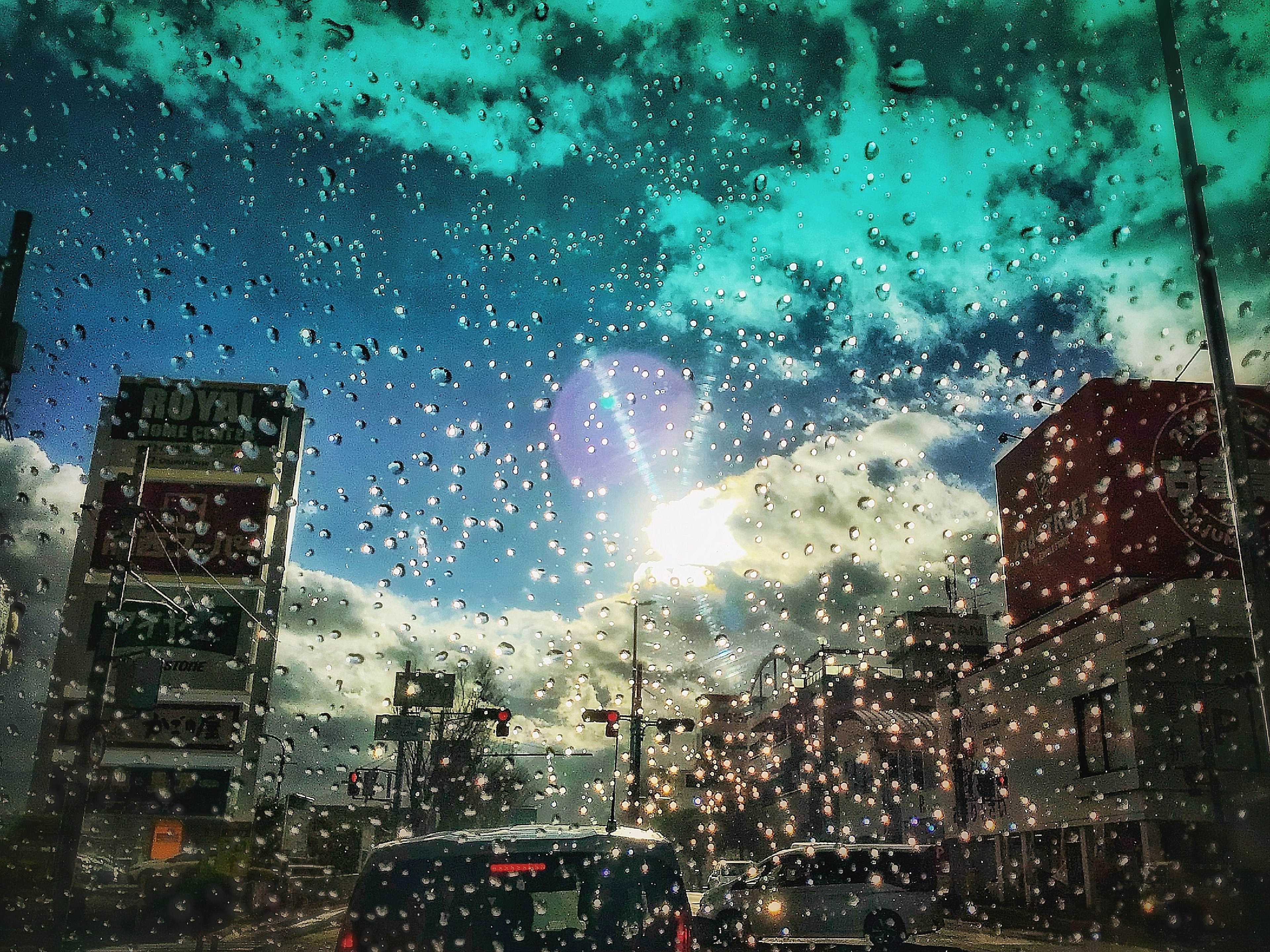 雨滴のついた窓越しに見える都市の風景と青空