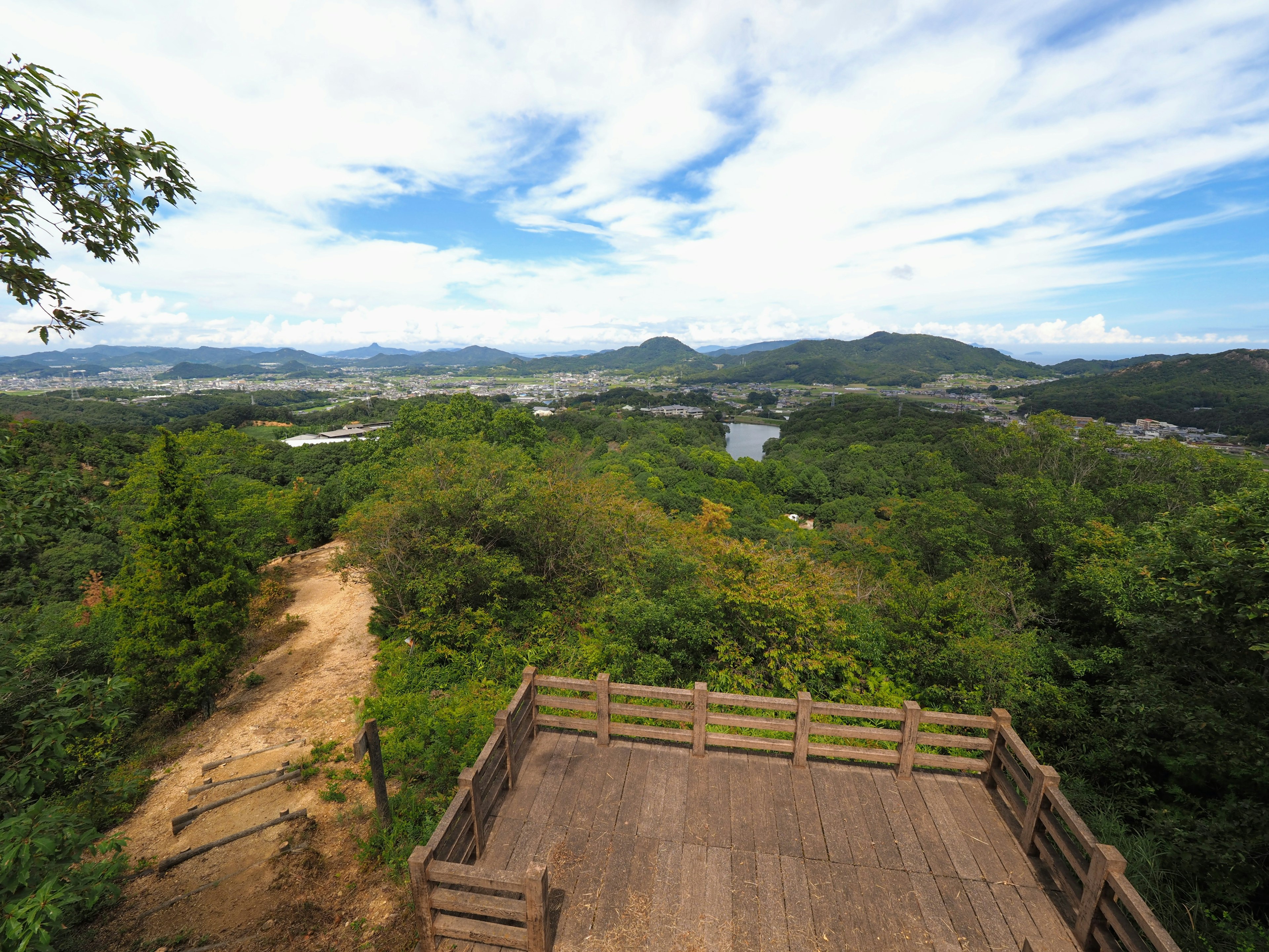 Vue panoramique depuis une plateforme d'observation en bois sur des collines verdoyantes et un ciel bleu