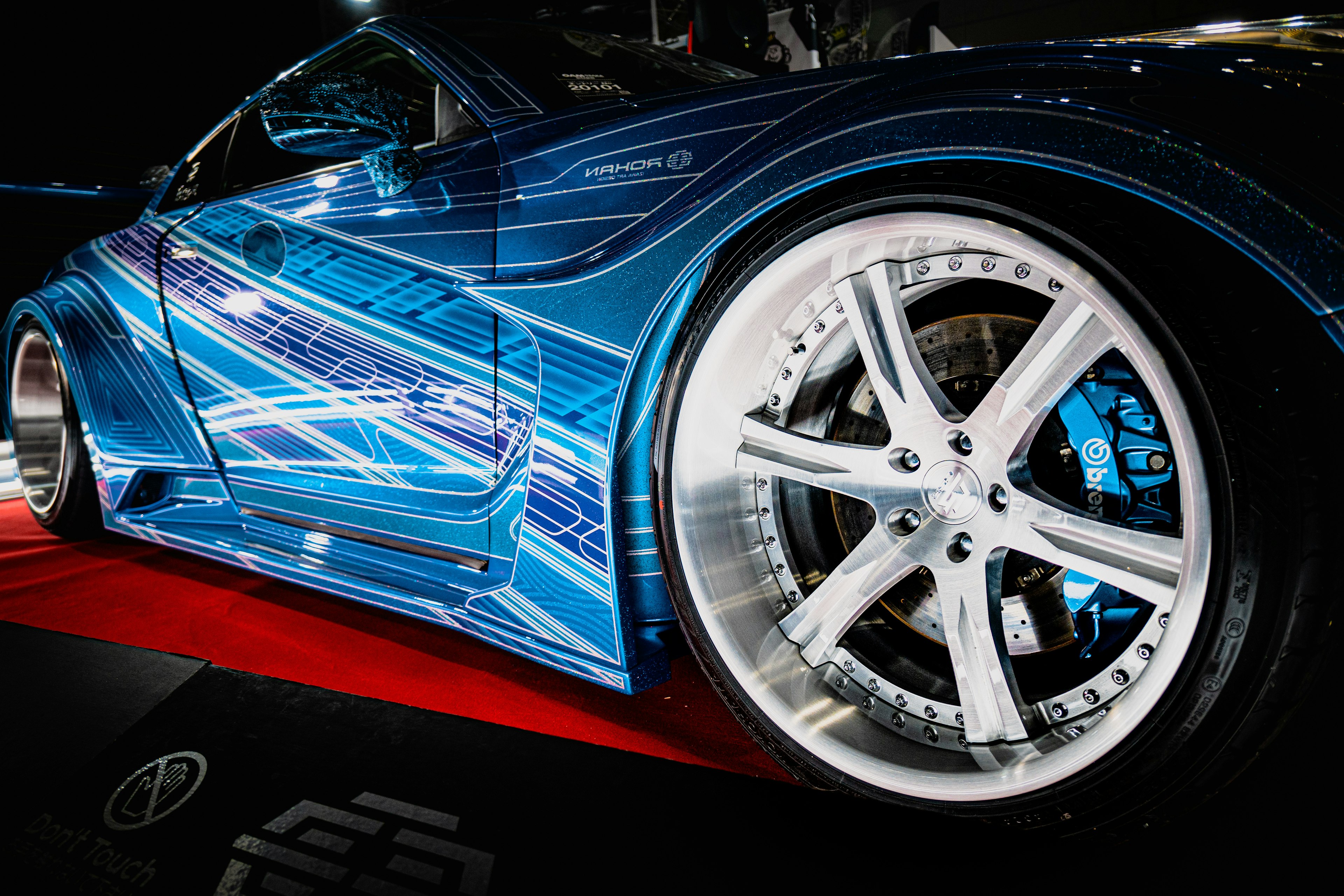 Close-up of a custom blue car showcasing detailed graphics and shiny wheels