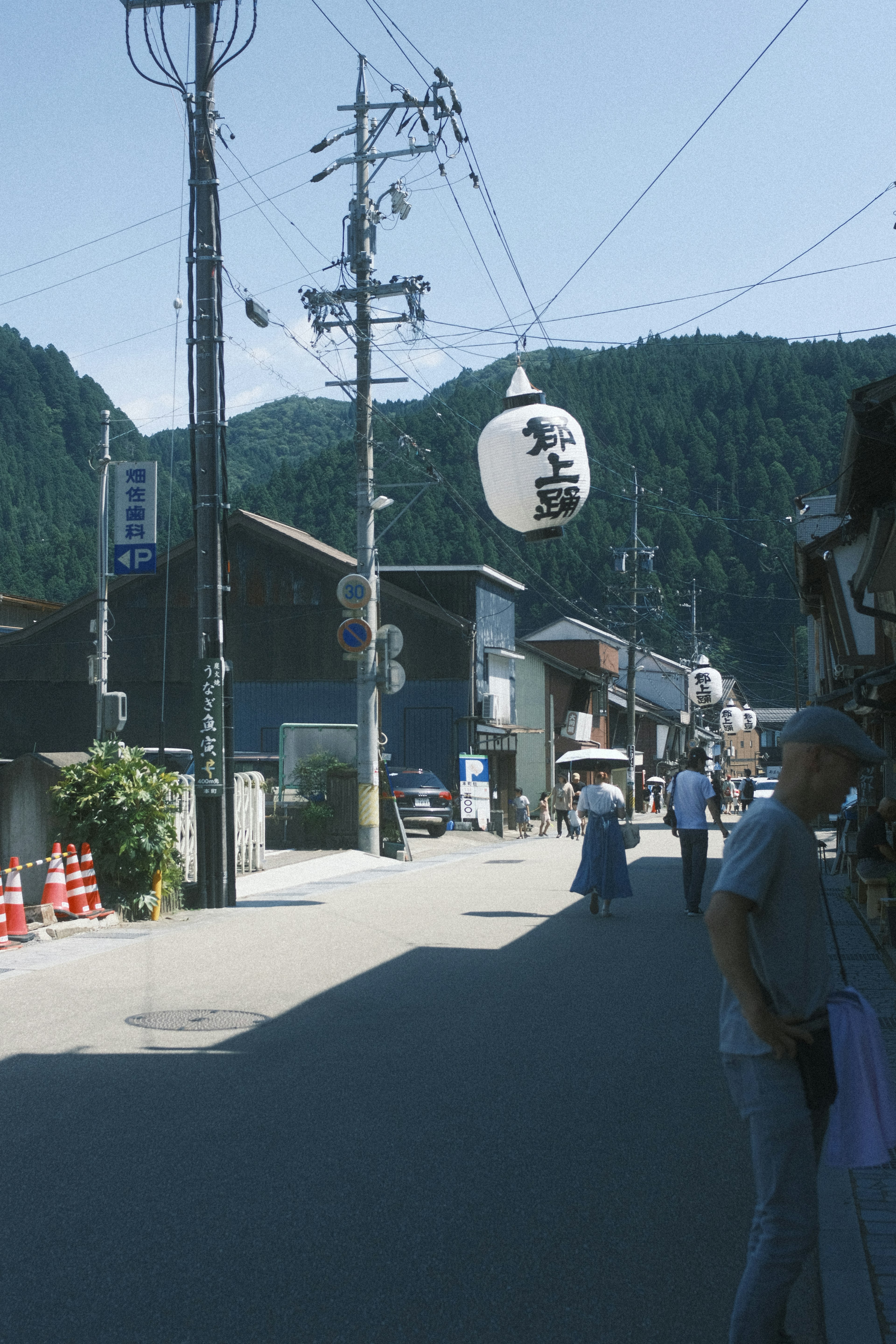 Street in rural Japan surrounded by mountains with a lantern and old buildings