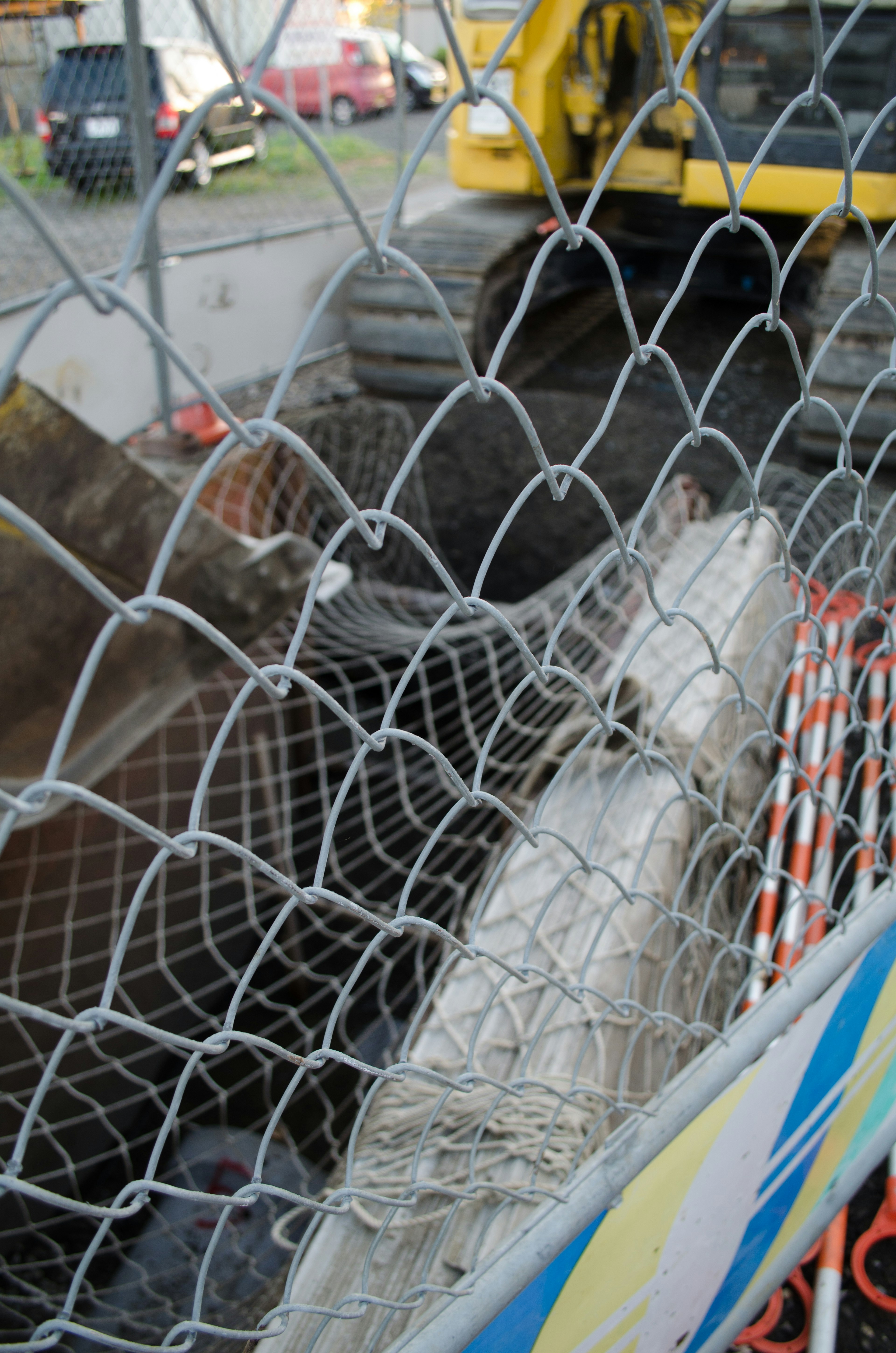 Construction site with heavy machinery and ongoing road work seen through a fence