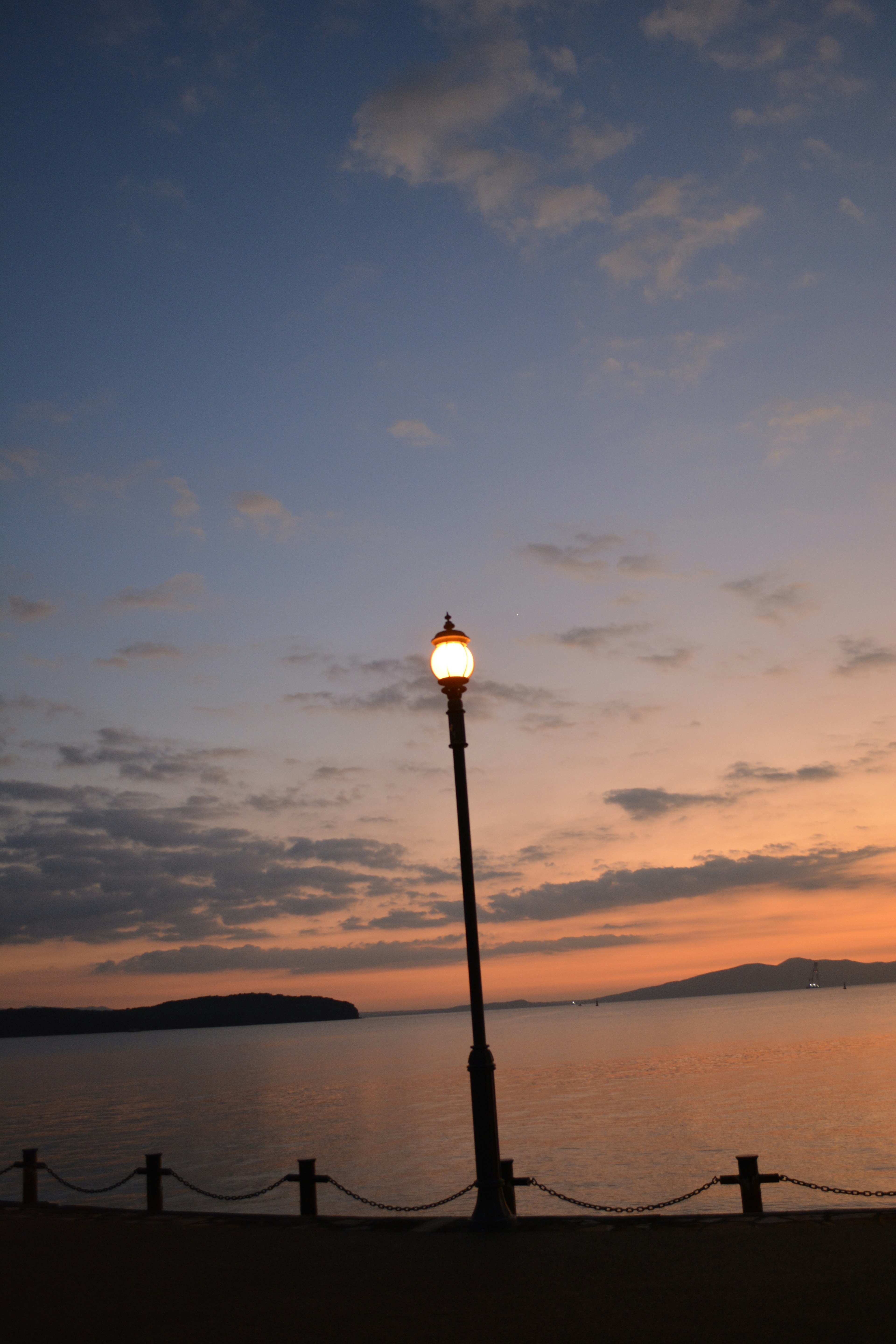 Eine Straßenlaterne am Wasser mit einem Sonnenuntergangshimmel