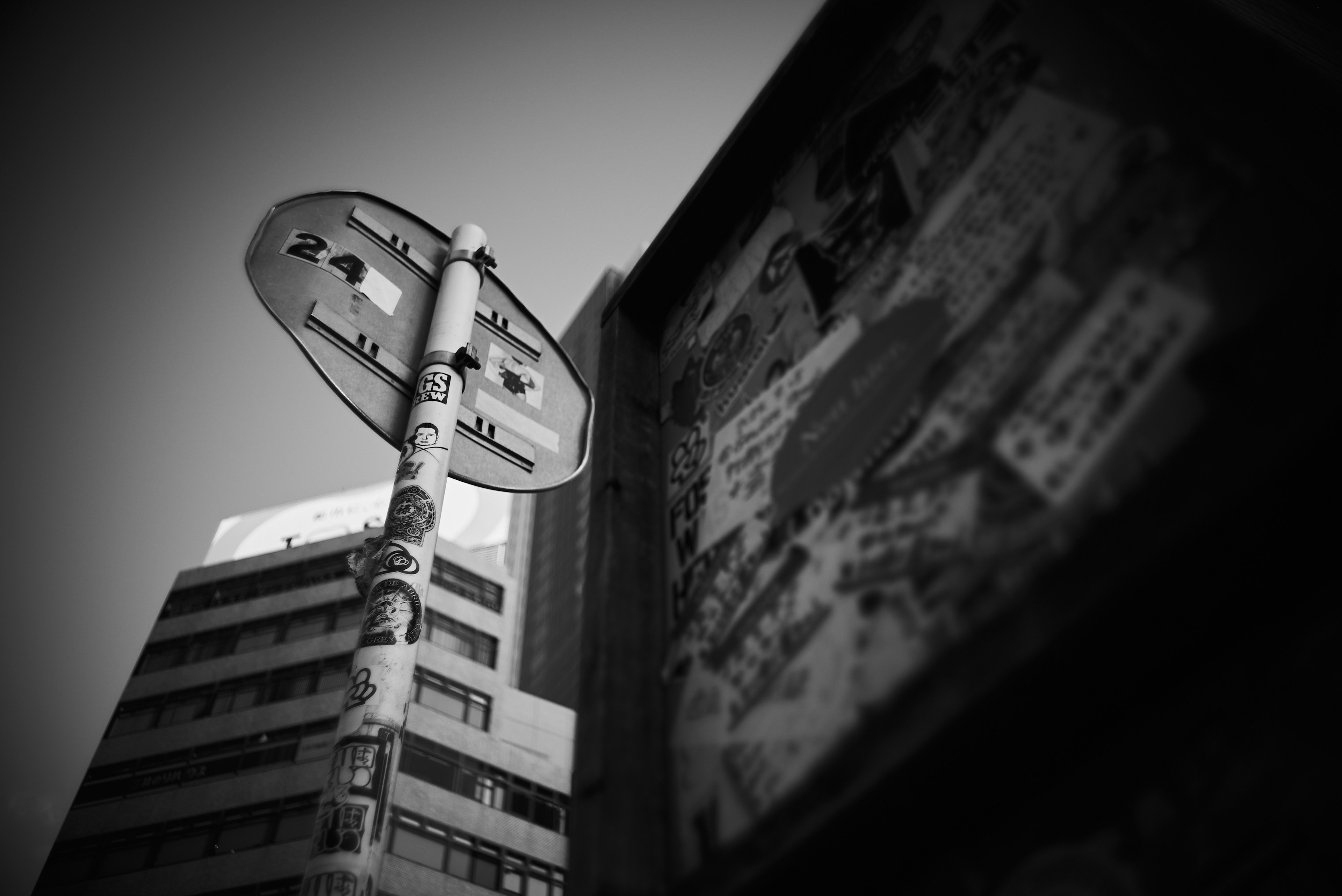 Paisaje urbano en blanco y negro con un letrero de parada de autobús y anuncios