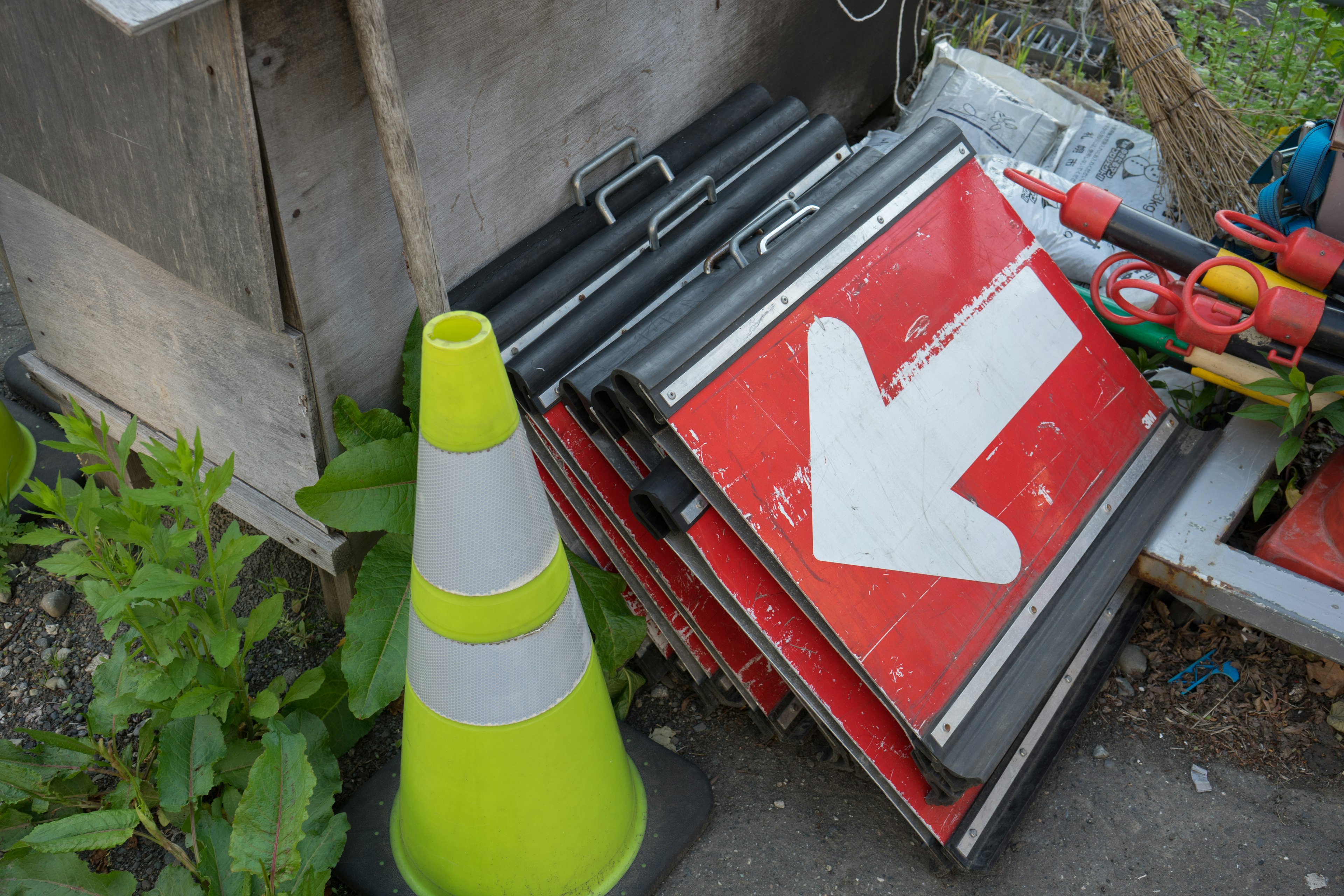 Stack of red directional signs with a green traffic cone