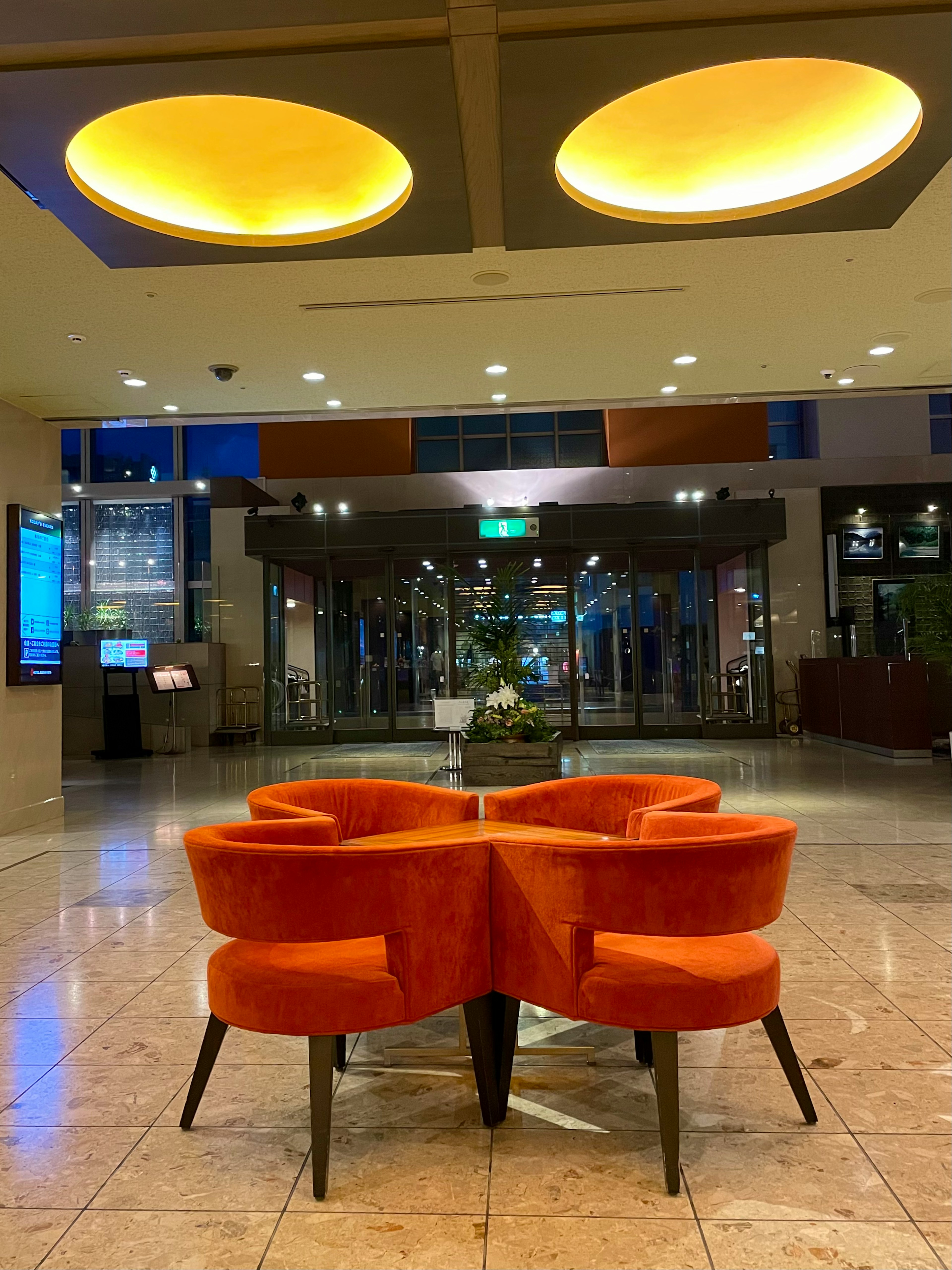 Bright lobby featuring orange chairs and simple ceiling design