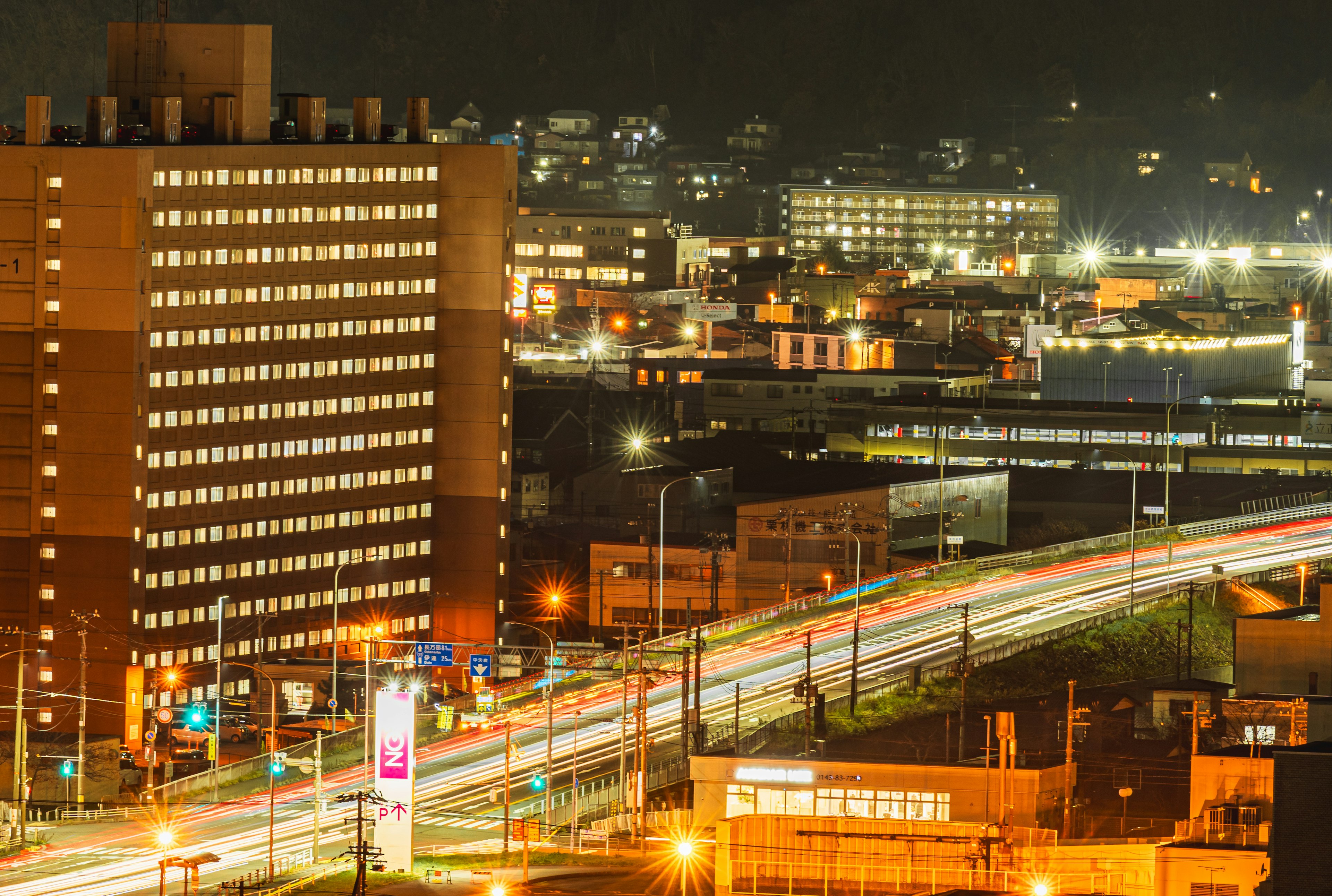 Nächtliche Stadtlandschaft mit Hochhäusern und fließendem Verkehr