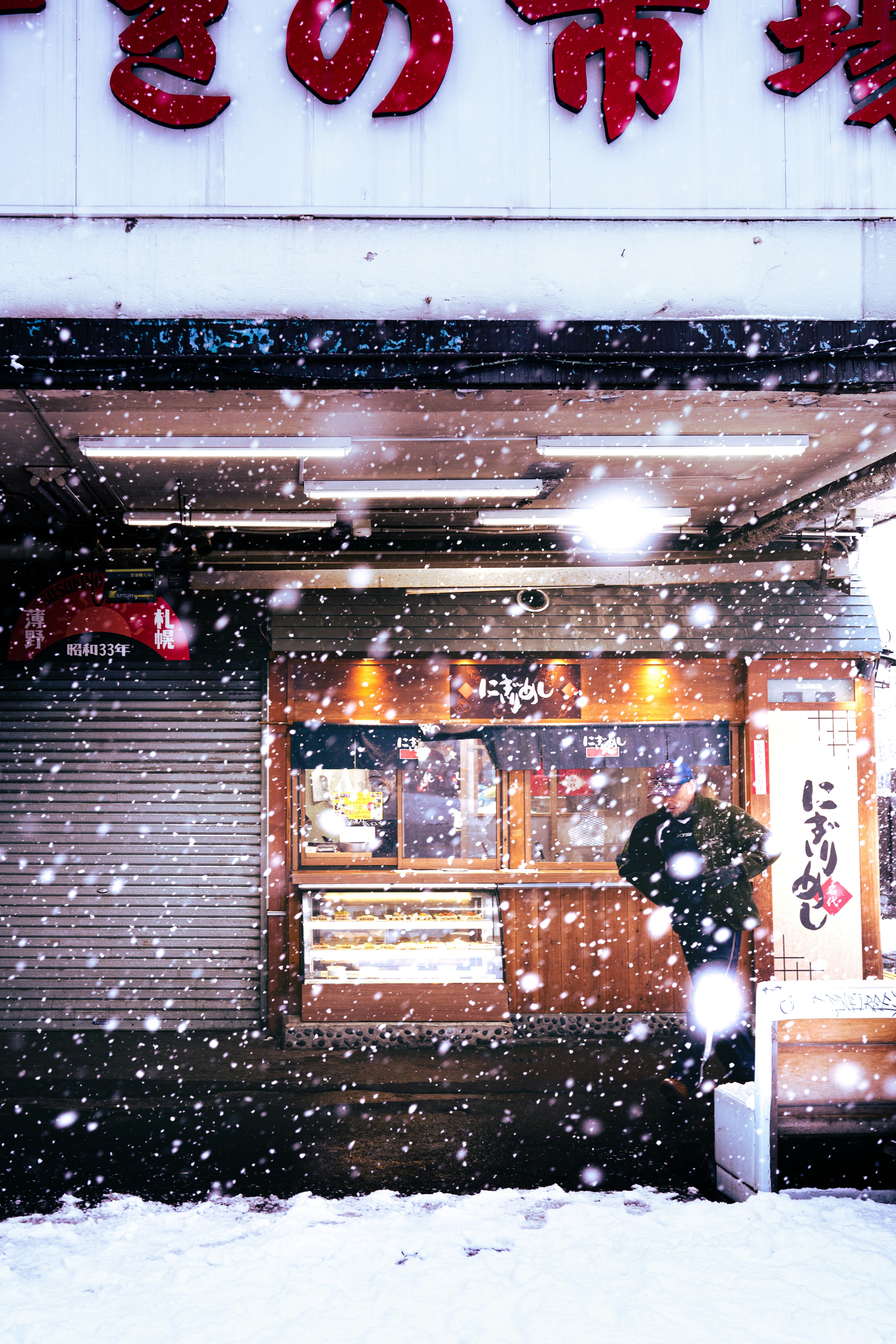 Wooden storefront with red signage in falling snow