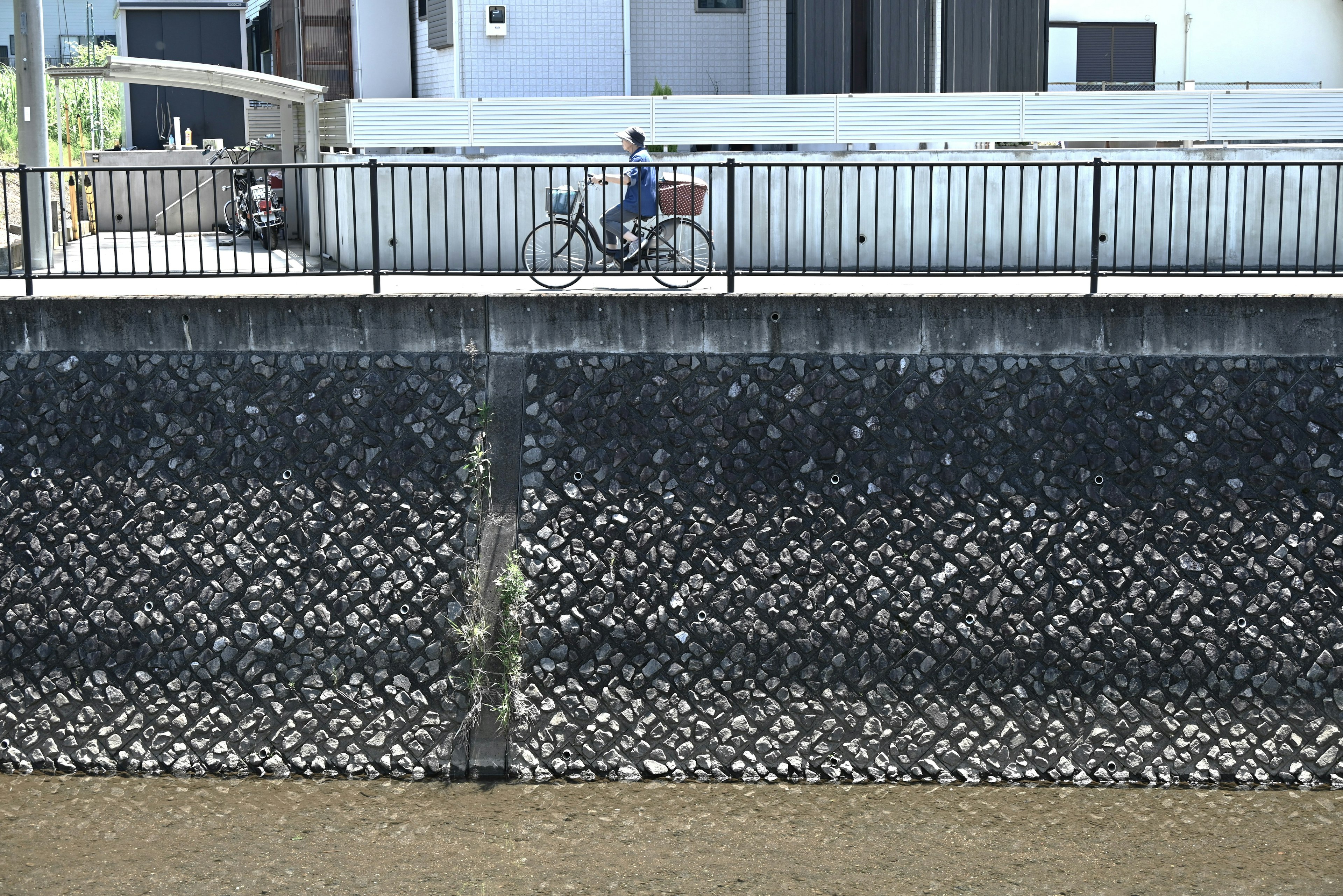 Eine Person, die auf einem Fahrrad neben einer Betonmauer an einem Gewässer fährt