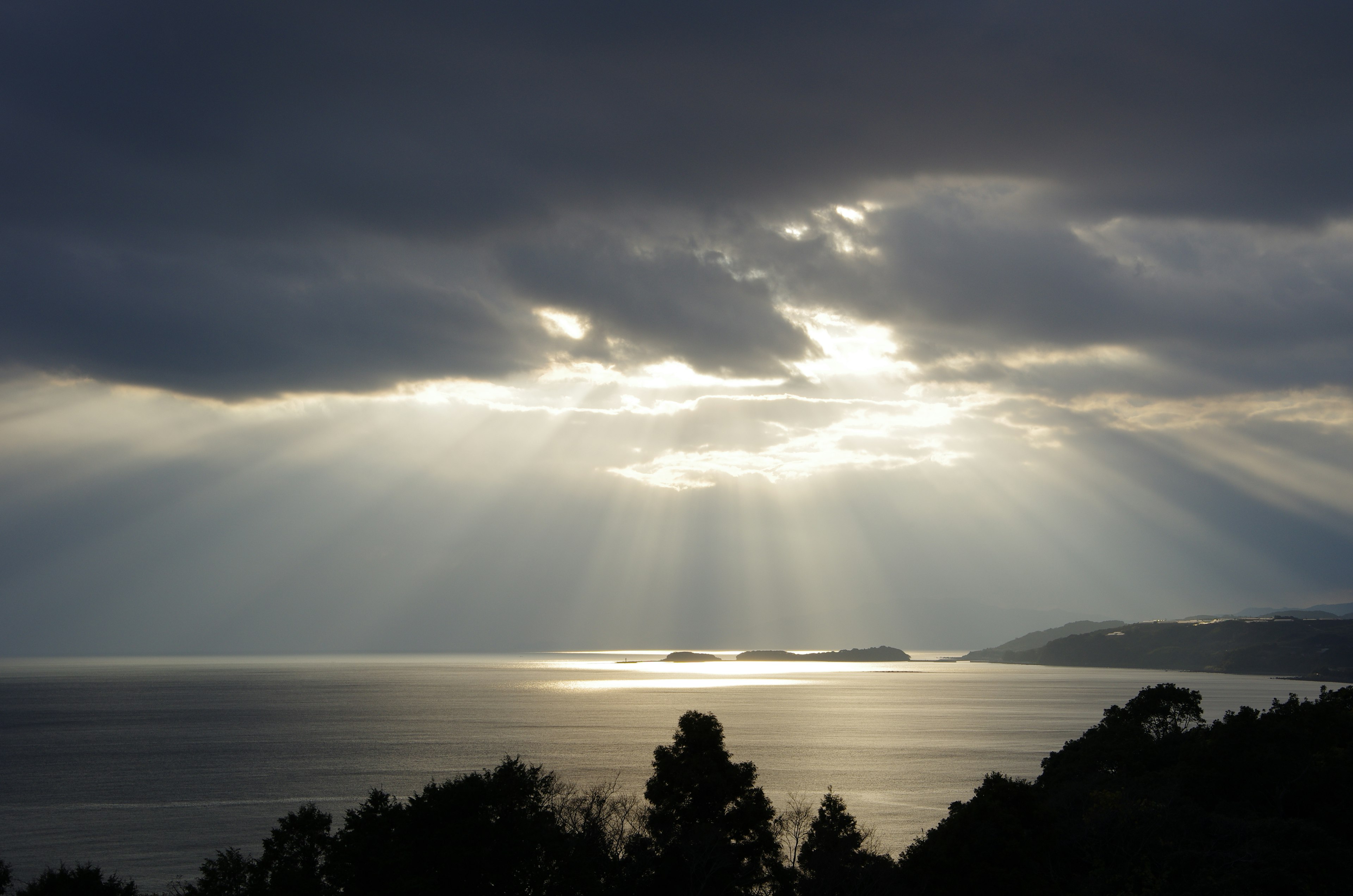 Sunlight breaking through dark clouds over a calm lake