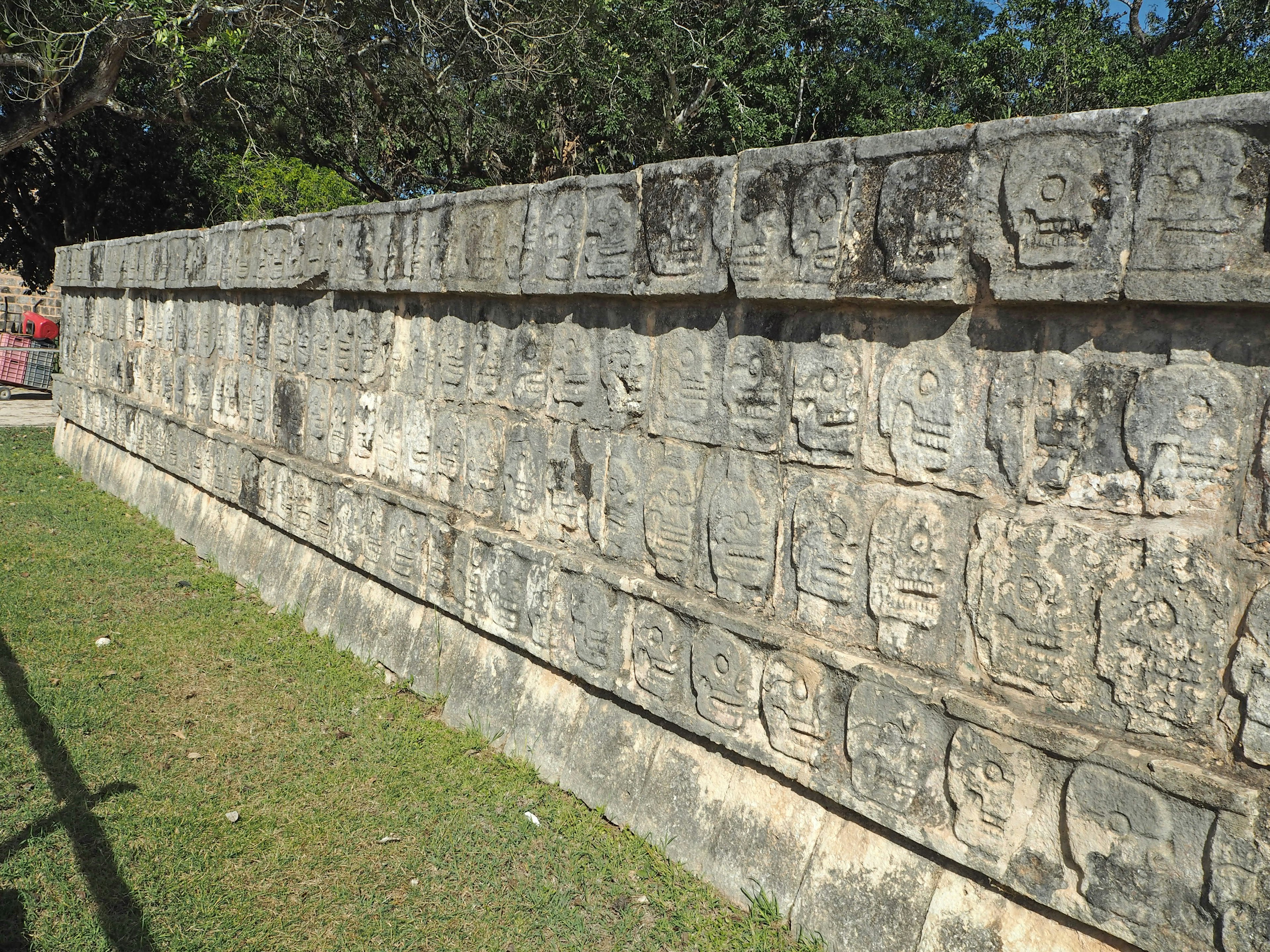 Antigua pared de piedra con intrincadas tallas sobre un fondo de hierba verde exuberante