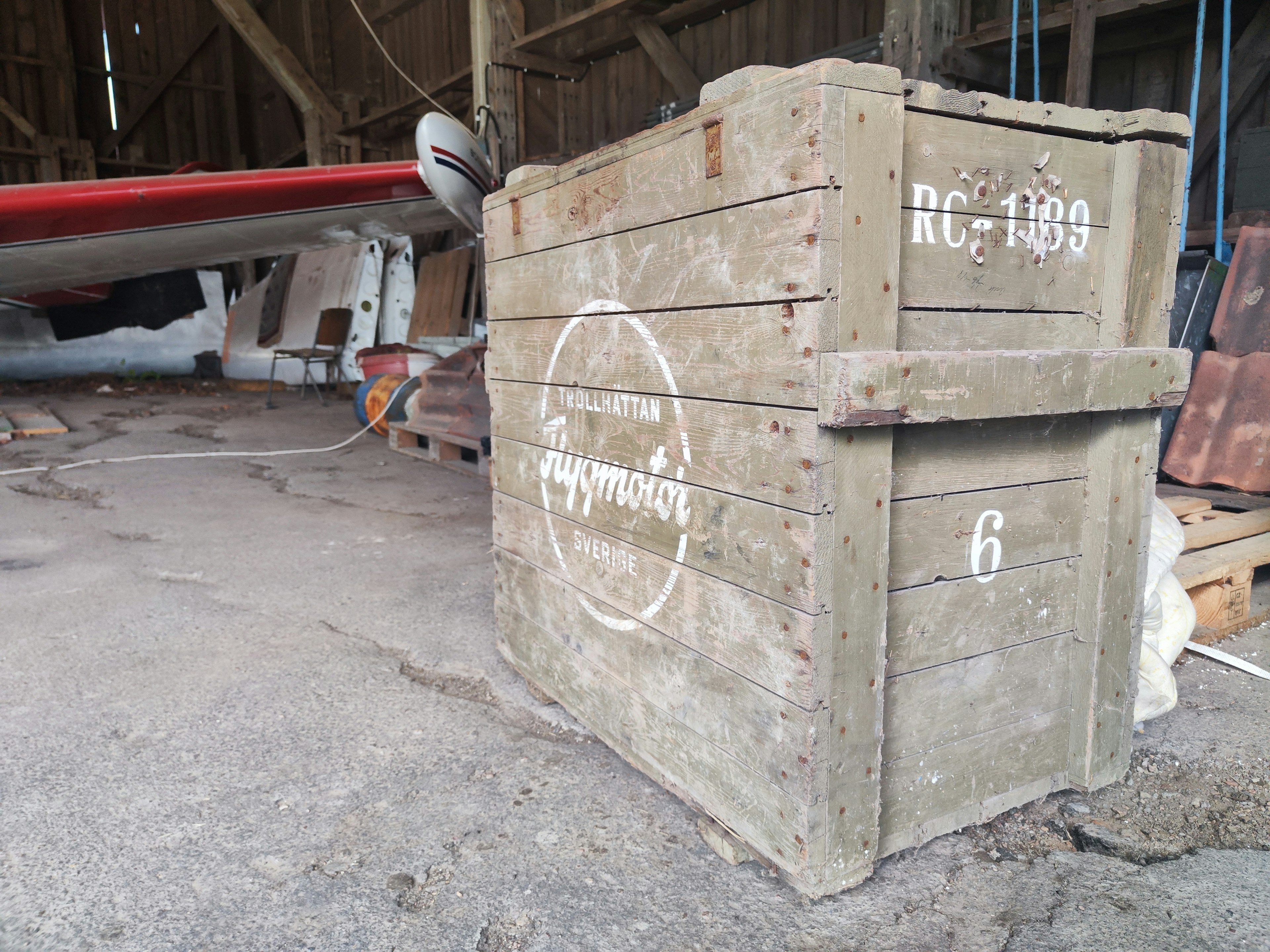 Una antigua caja de madera ubicada en un granero que presenta la etiqueta RC-109 y un logo circular