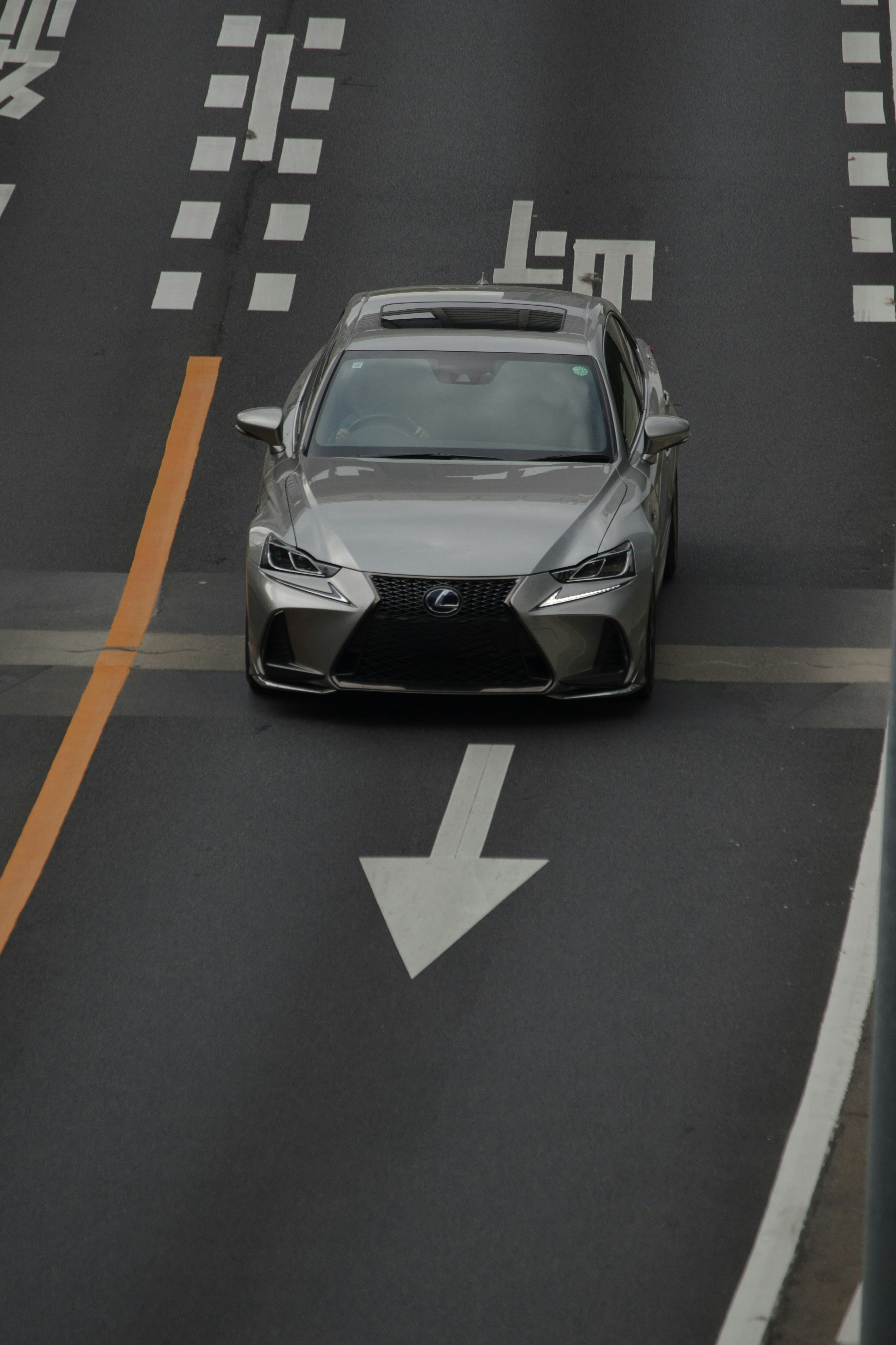 Silver Lexus car on the road with directional arrow signs