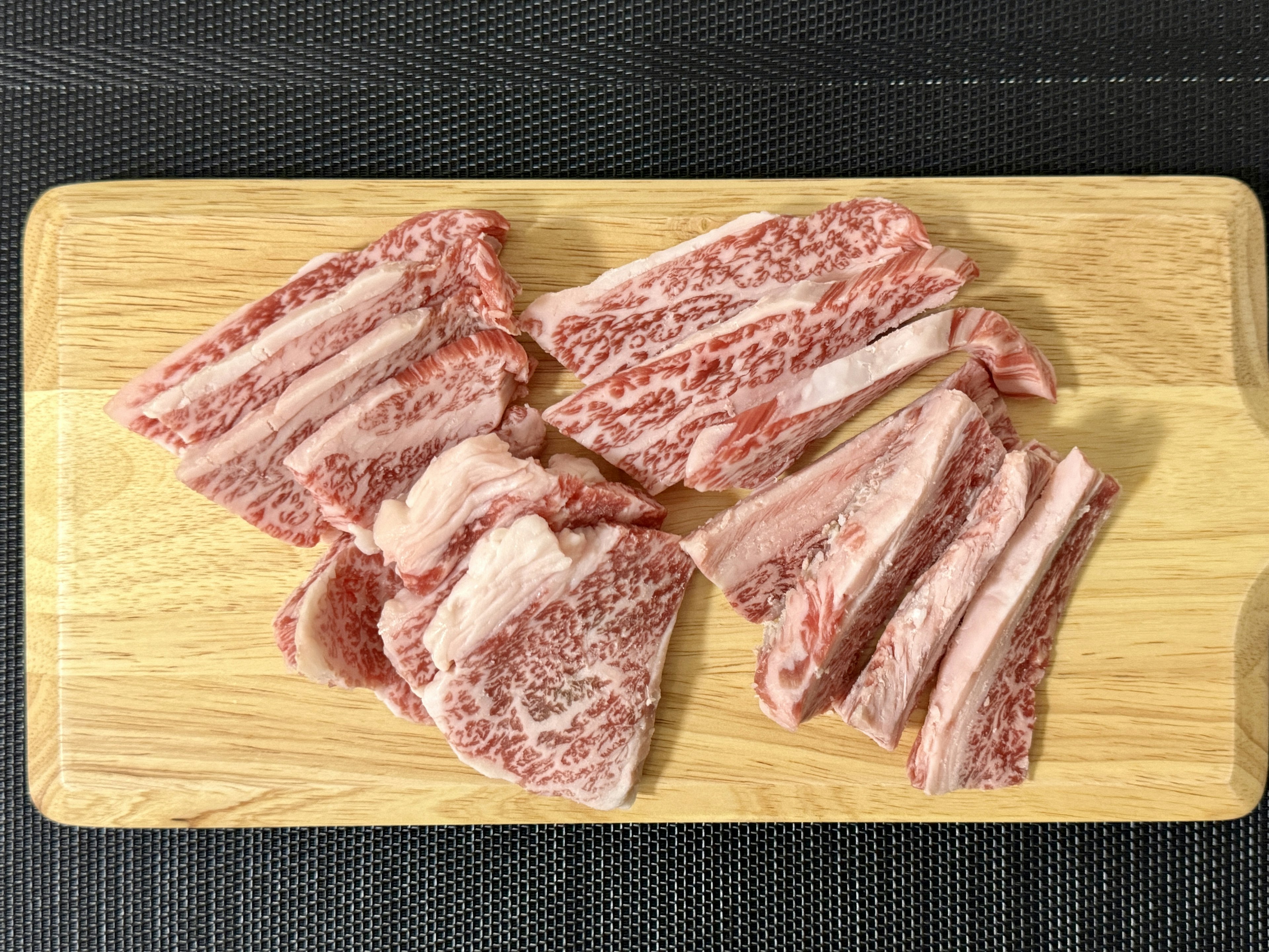 Carne affettata sottilmente disposta su un tagliere di legno