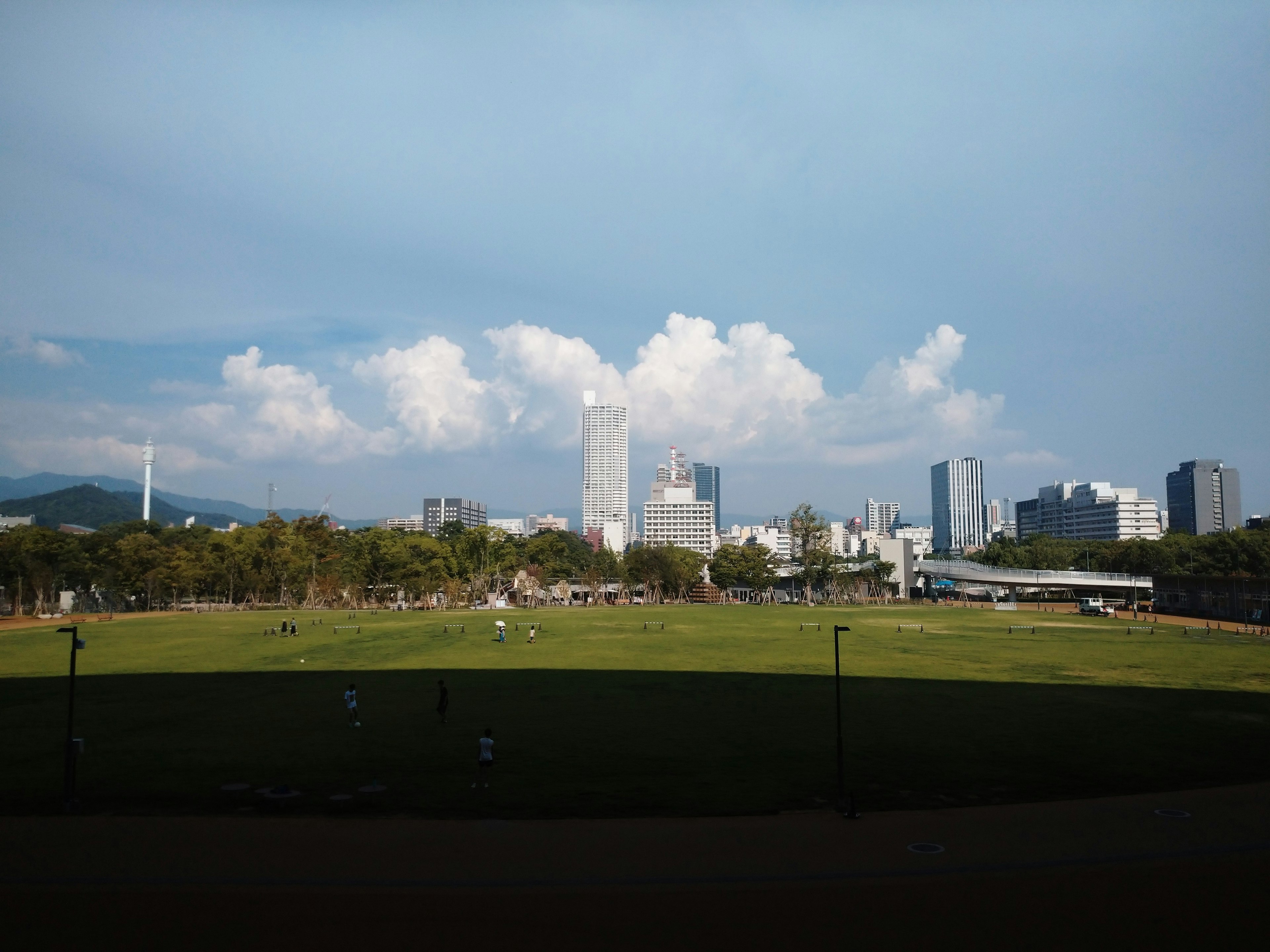 Stadtansicht mit hohen Gebäuden unter blauem Himmel und weißen Wolken