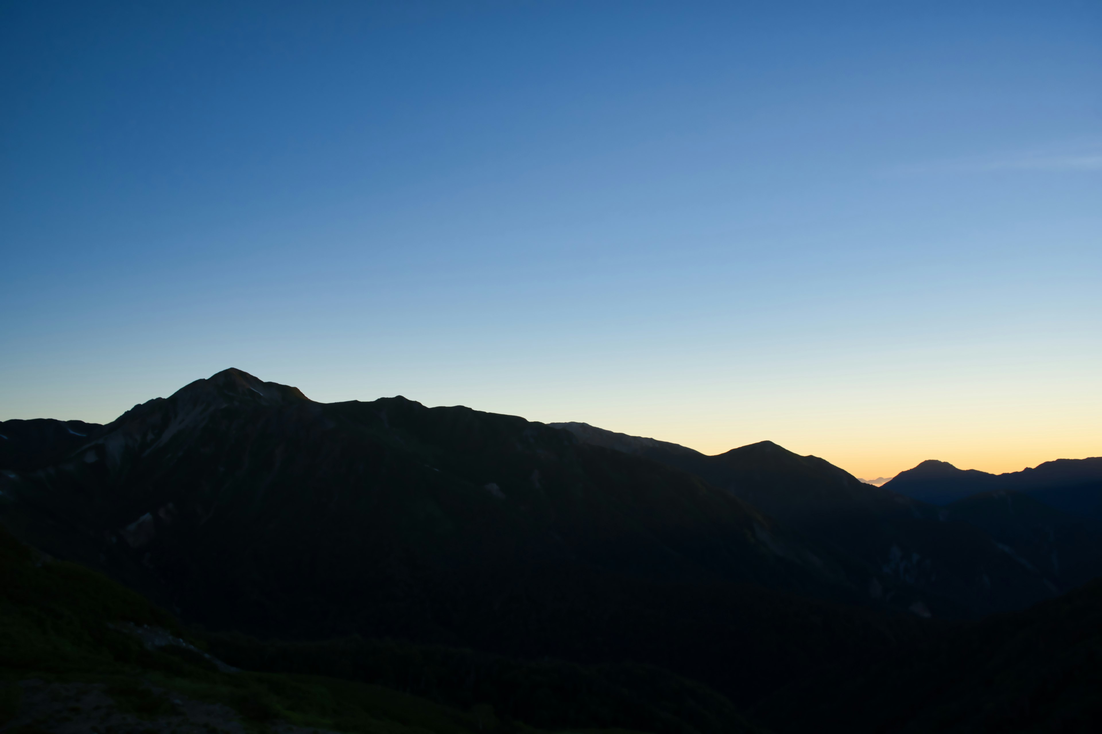 山々のシルエットが夕焼けの空に映える風景