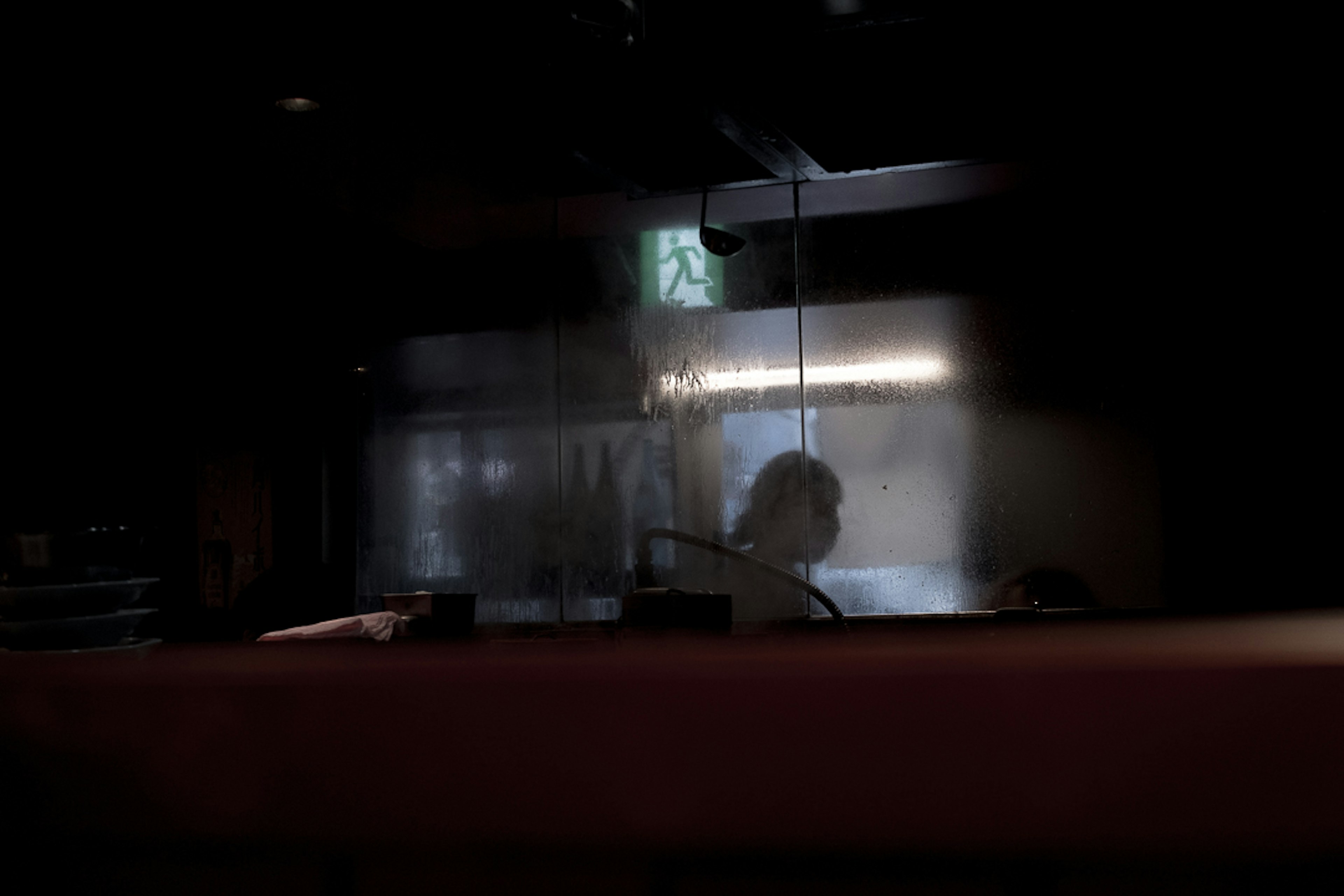 Silhouette of a person behind a translucent barrier in a dimly lit space