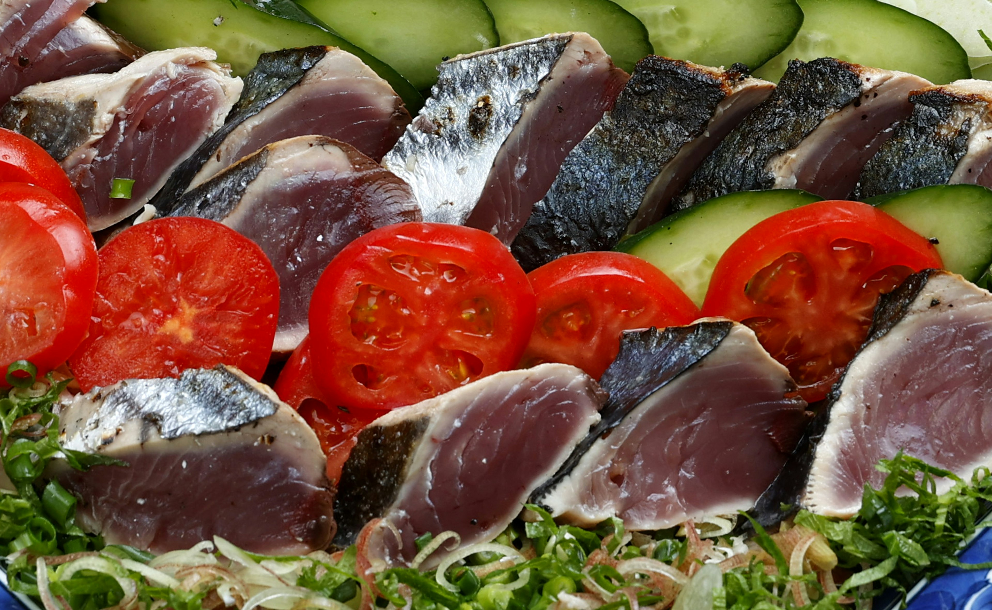 Fresh sashimi and vegetable platter featuring vibrant tomatoes and cucumbers