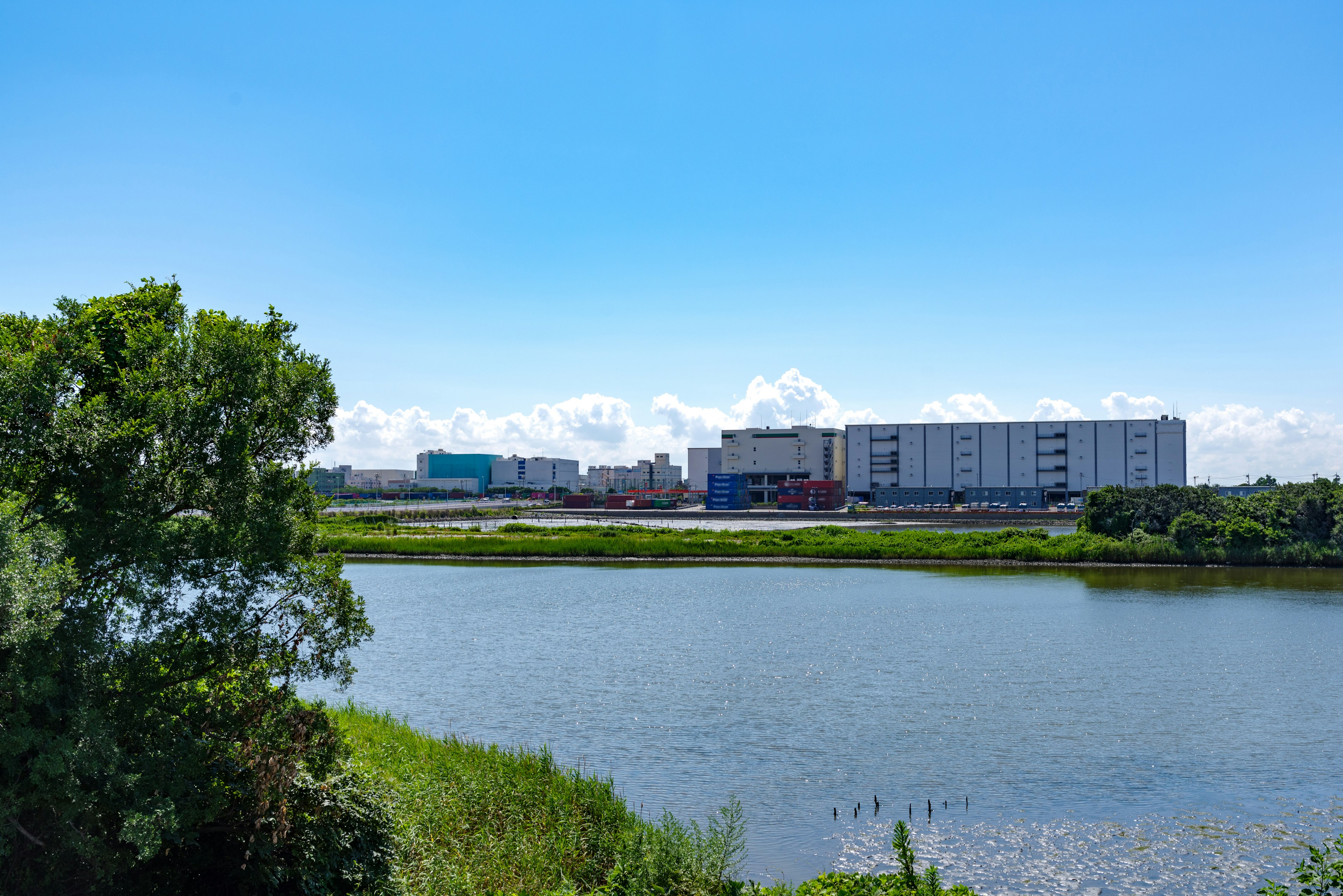 Pemandangan kota modern di sepanjang sungai dengan vegetasi subur dan langit biru cerah