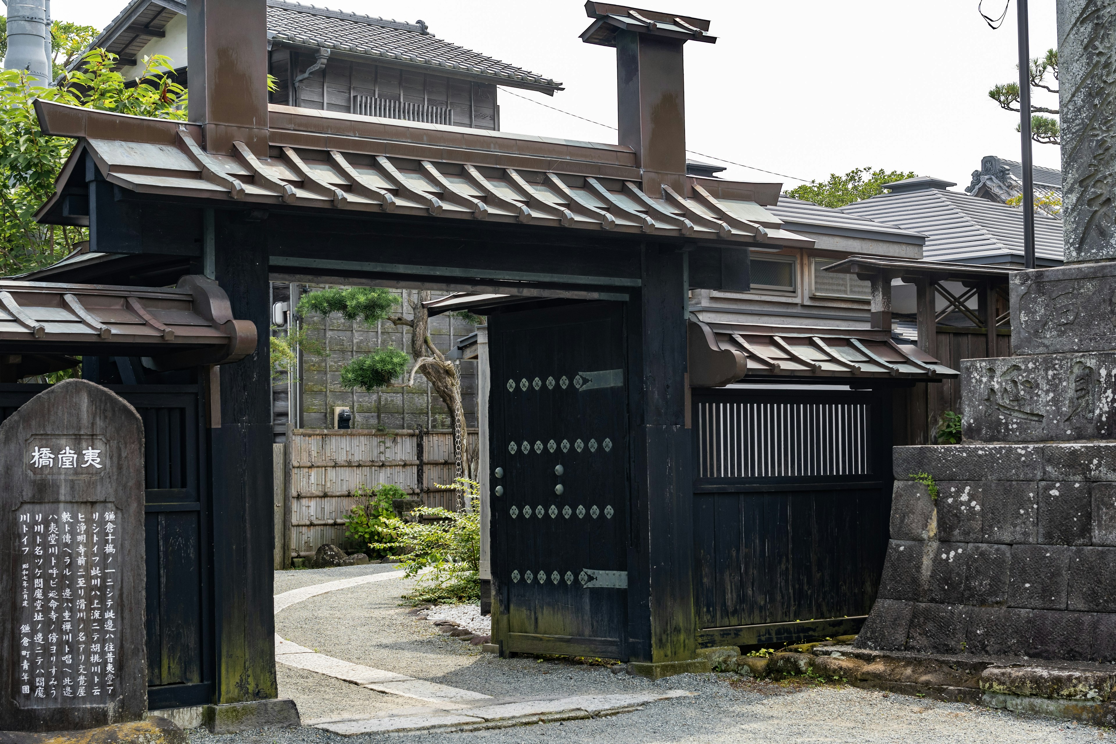 Traditional Japanese gate with a stone pathway and greenery